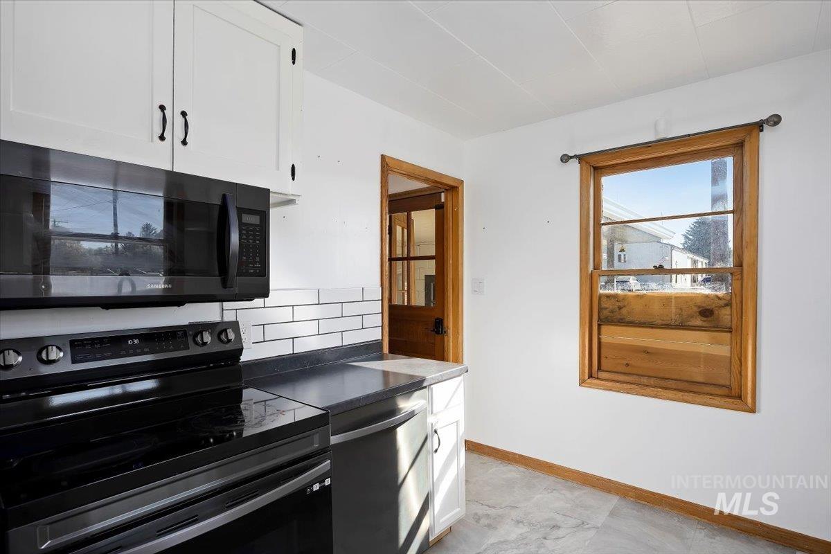 Kitchen with range with electric stovetop, white cabinets, dark countertops, and tasteful backsplash