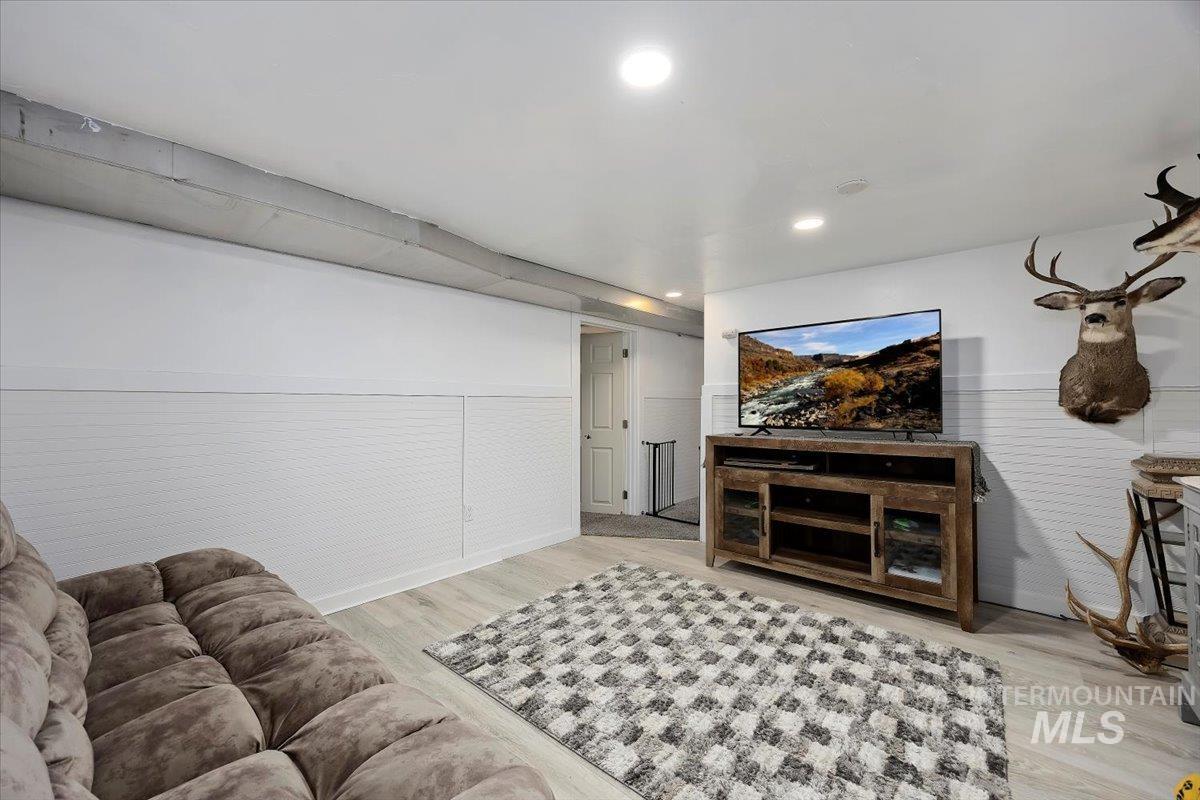 Living room with light wood-style flooring, a wainscoted wall, and recessed lighting