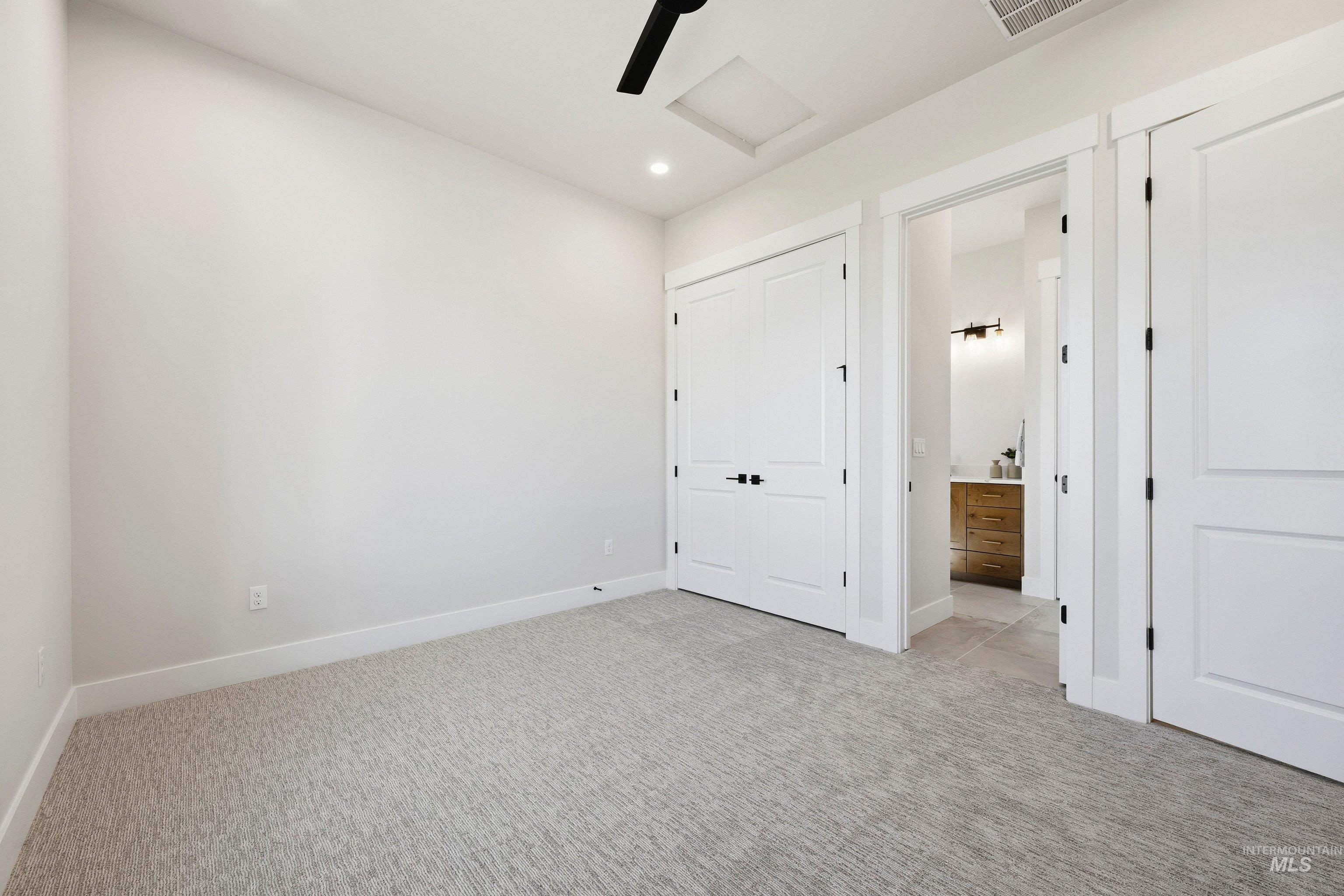 Unfurnished bedroom with light colored carpet, a closet, ceiling fan, recessed lighting, and ensuite bathroom