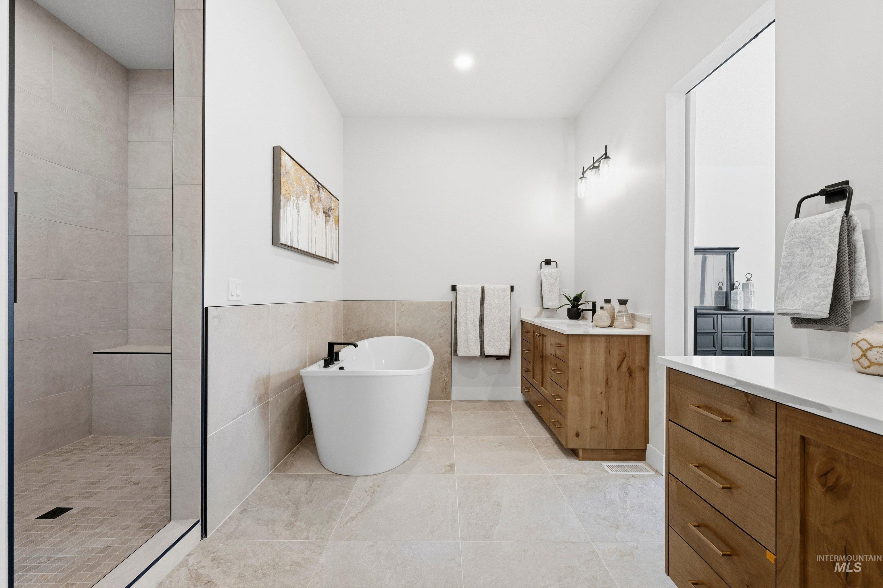 Bathroom featuring vanity, tile walls, tiled shower, a freestanding bath, and recessed lighting