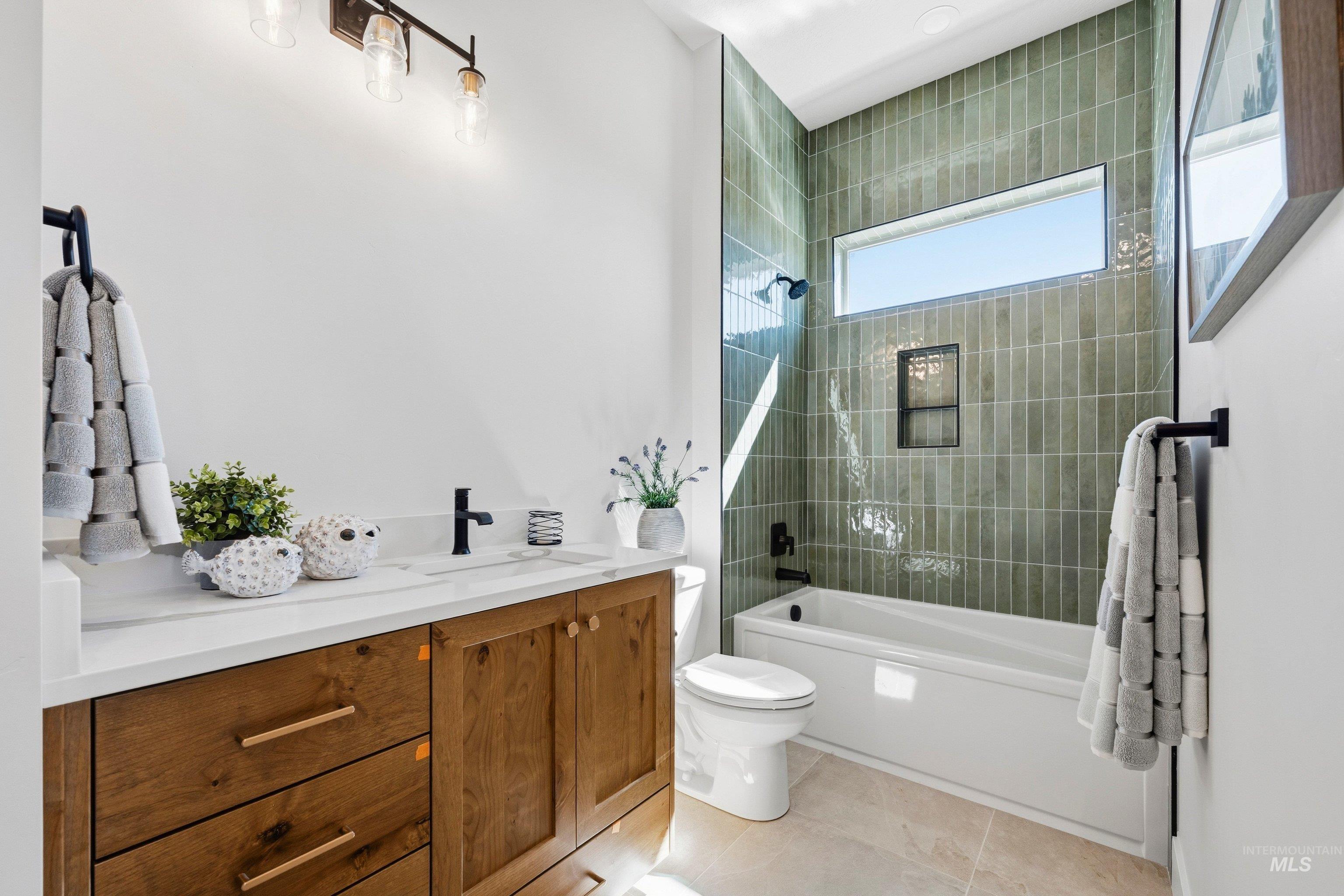 Full bath featuring vanity, washtub / shower combination, and light tile patterned floors