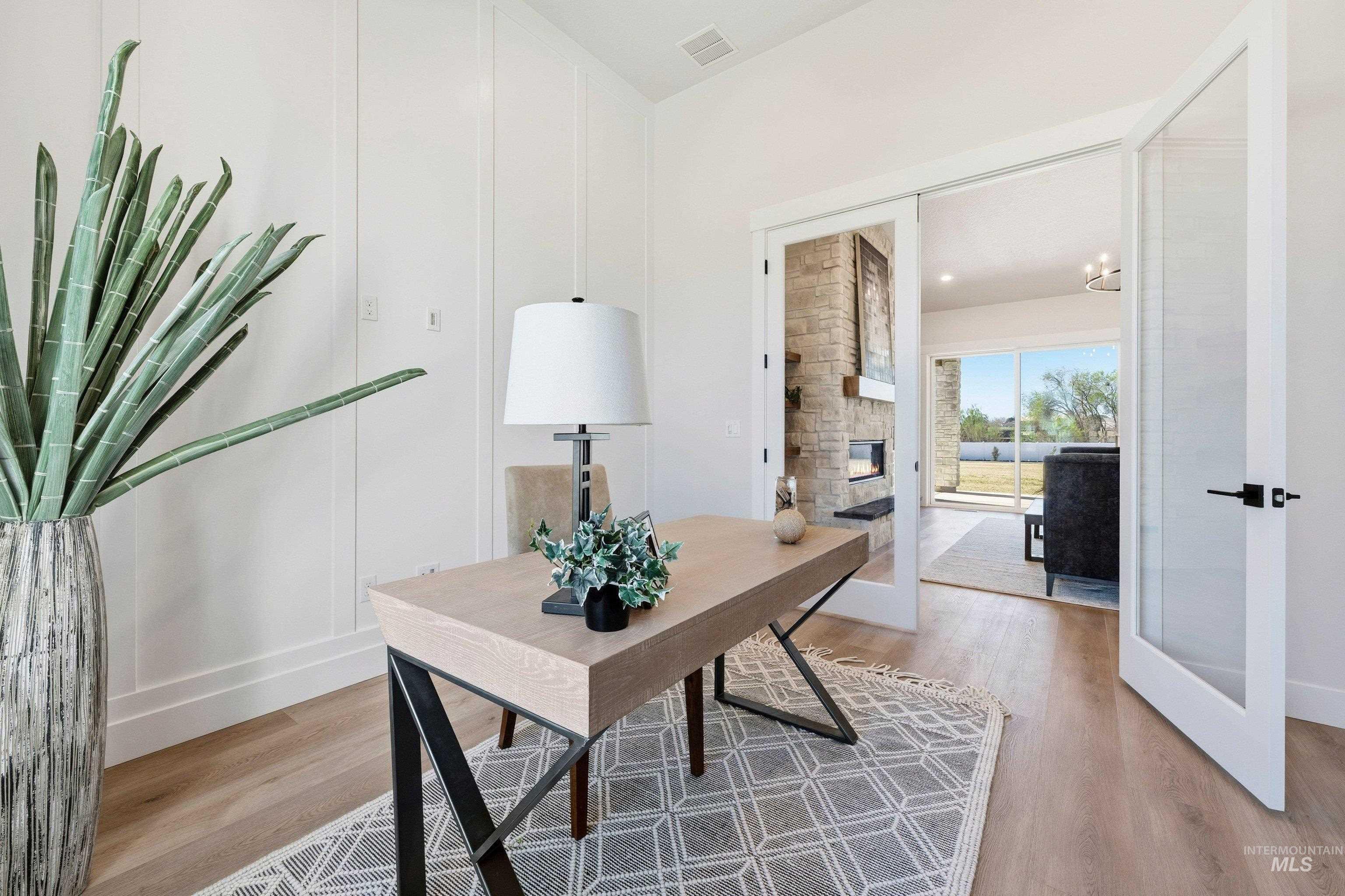 Home office with light wood finished floors, a stone fireplace, and french doors