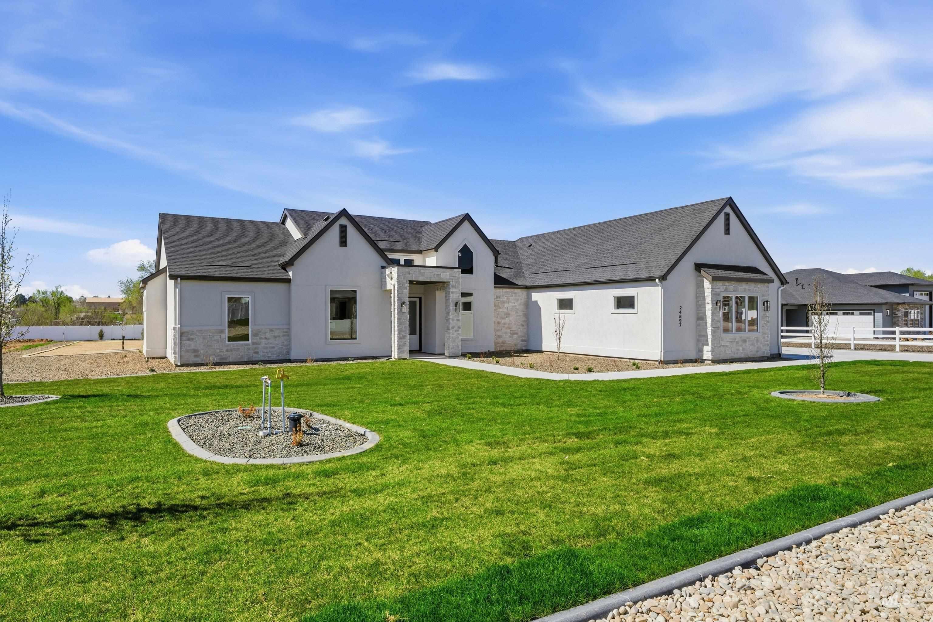 Modern inspired farmhouse featuring stucco siding, stone siding, and roof with shingles