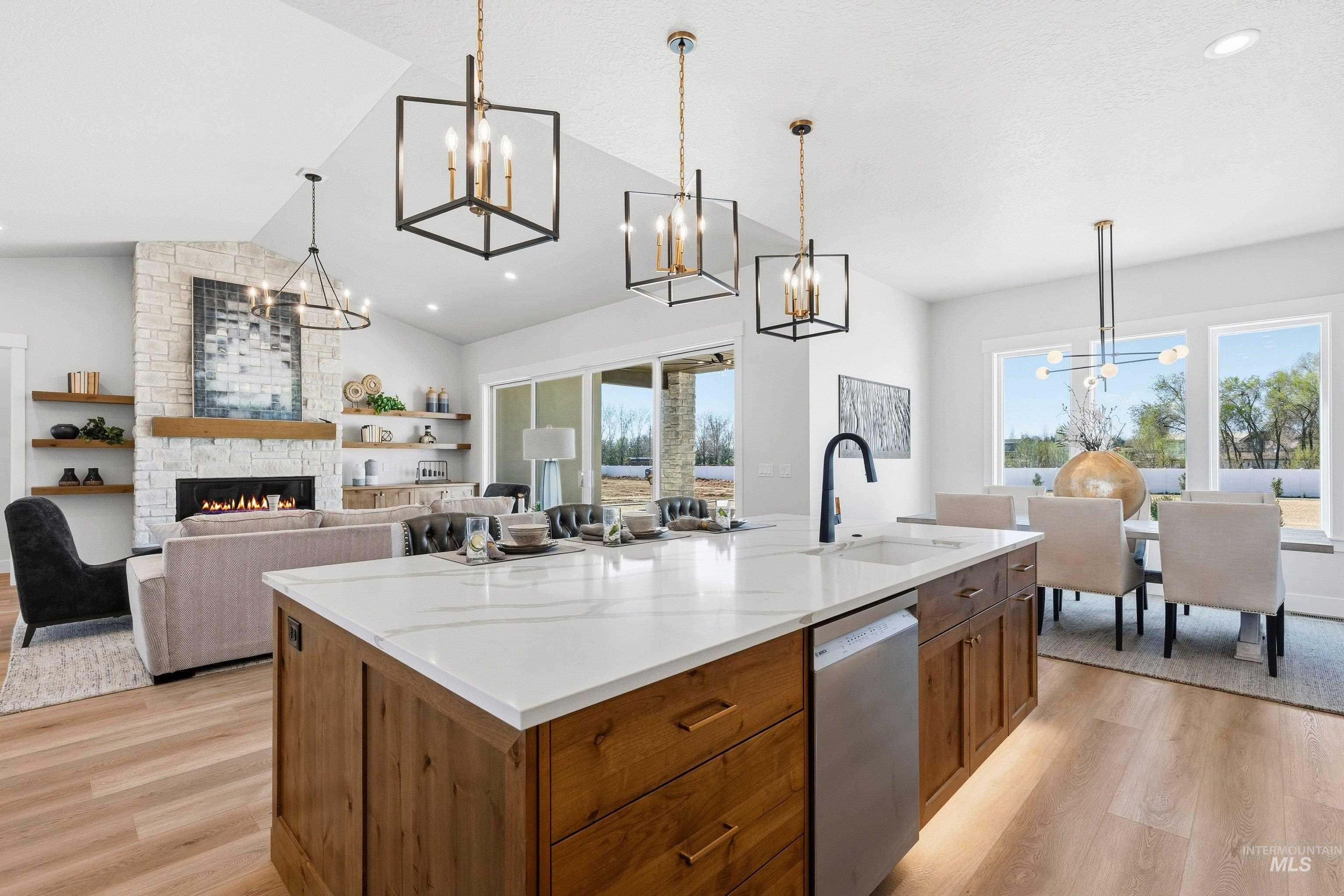 Kitchen featuring hanging lights, light wood-style floors, open floor plan, a stone fireplace, and stainless steel dishwasher