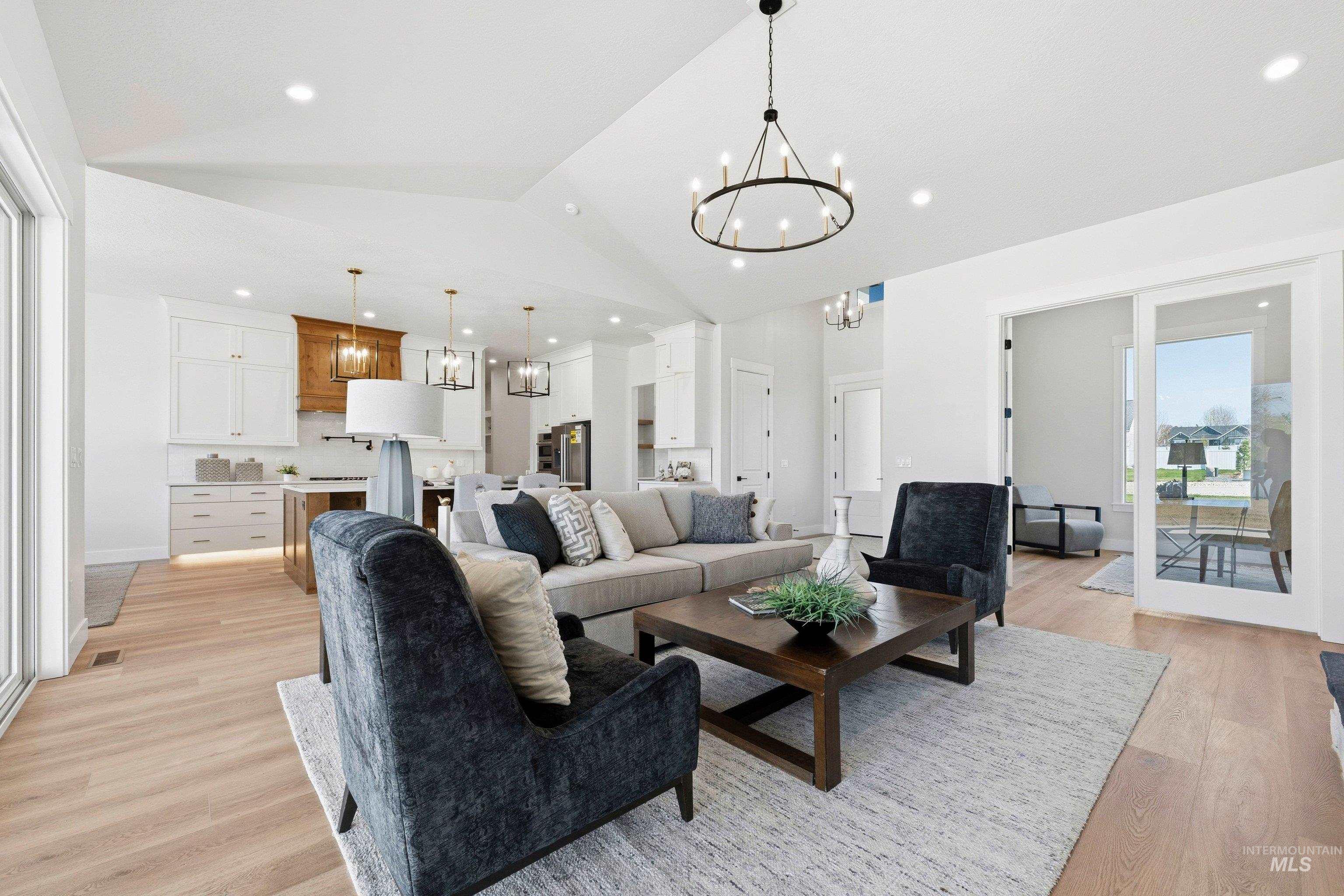 Living area with hanging lights, light wood-type flooring, and lofted ceiling