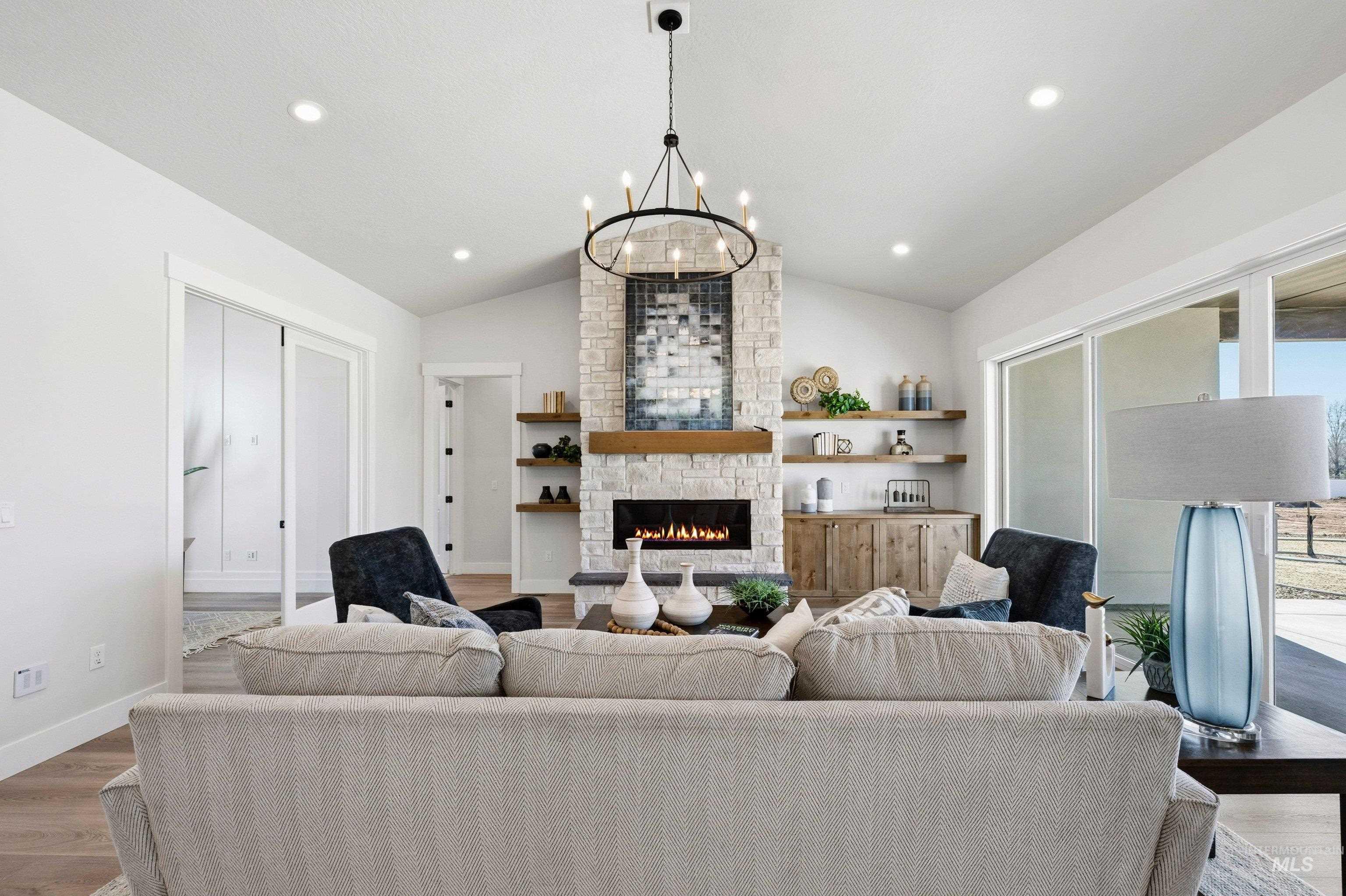 Living room with wood finished floors, a chandelier, lofted ceiling, and a fireplace