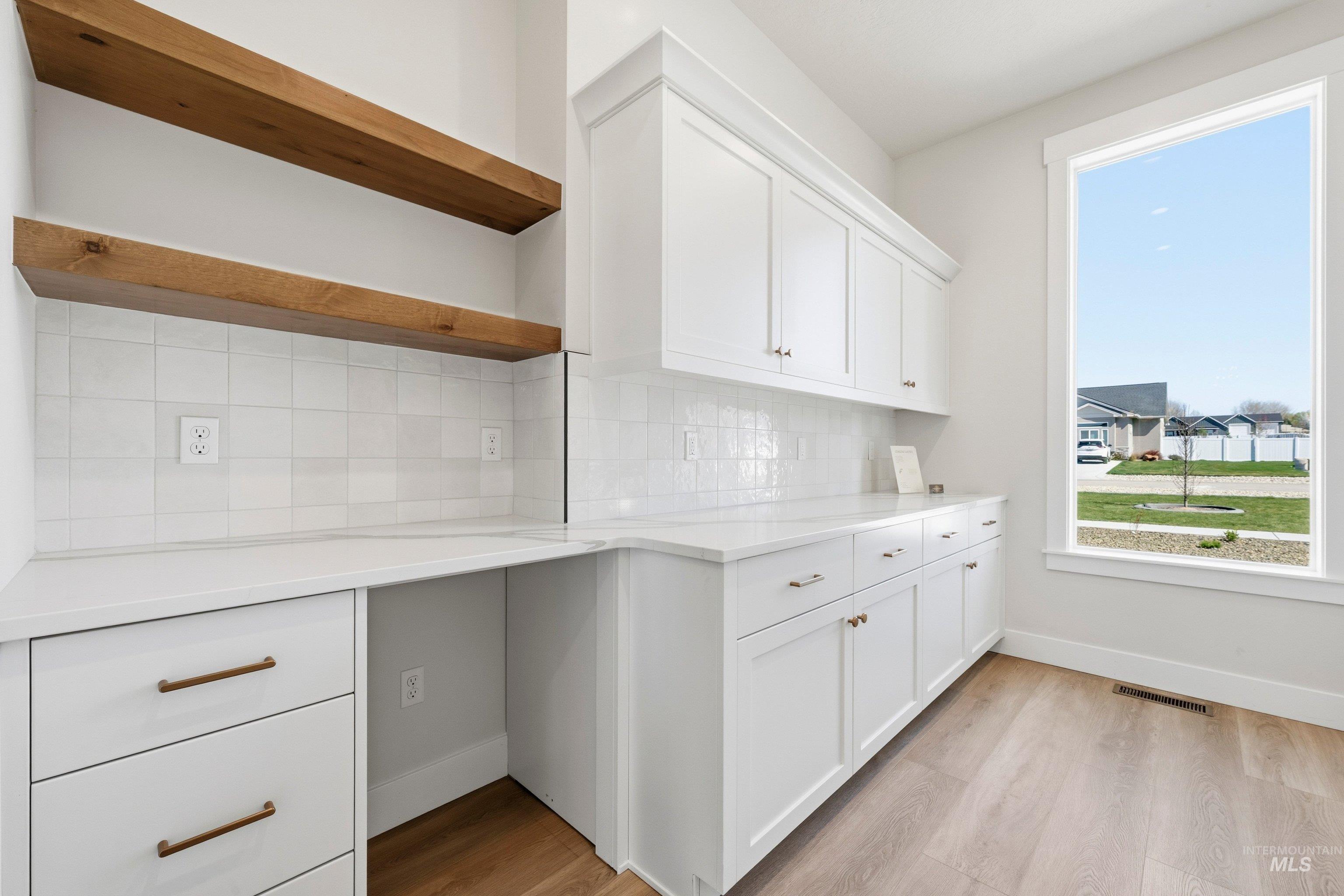 Kitchen featuring white cabinetry, open shelves, light wood-type flooring, and tasteful backsplash