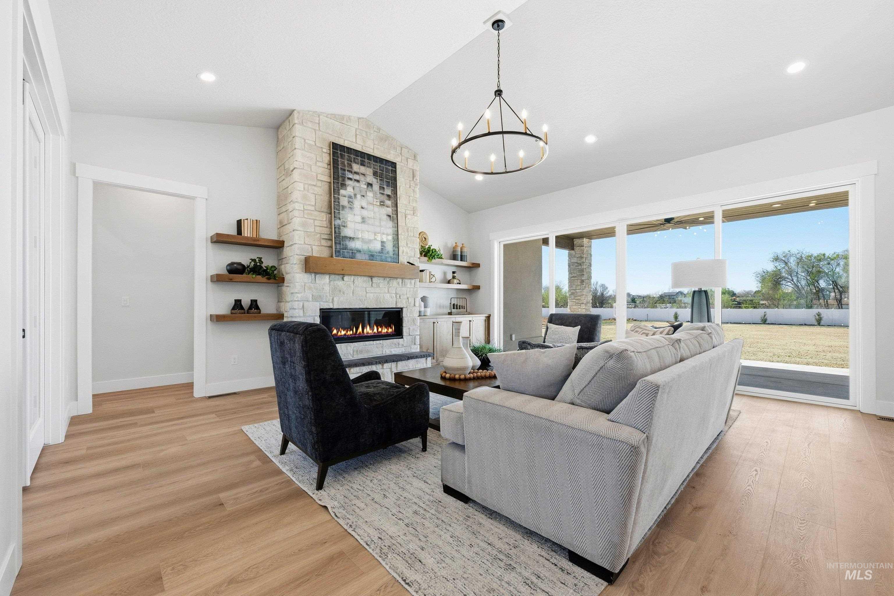 Living room with light wood finished floors, a chandelier, and a fireplace