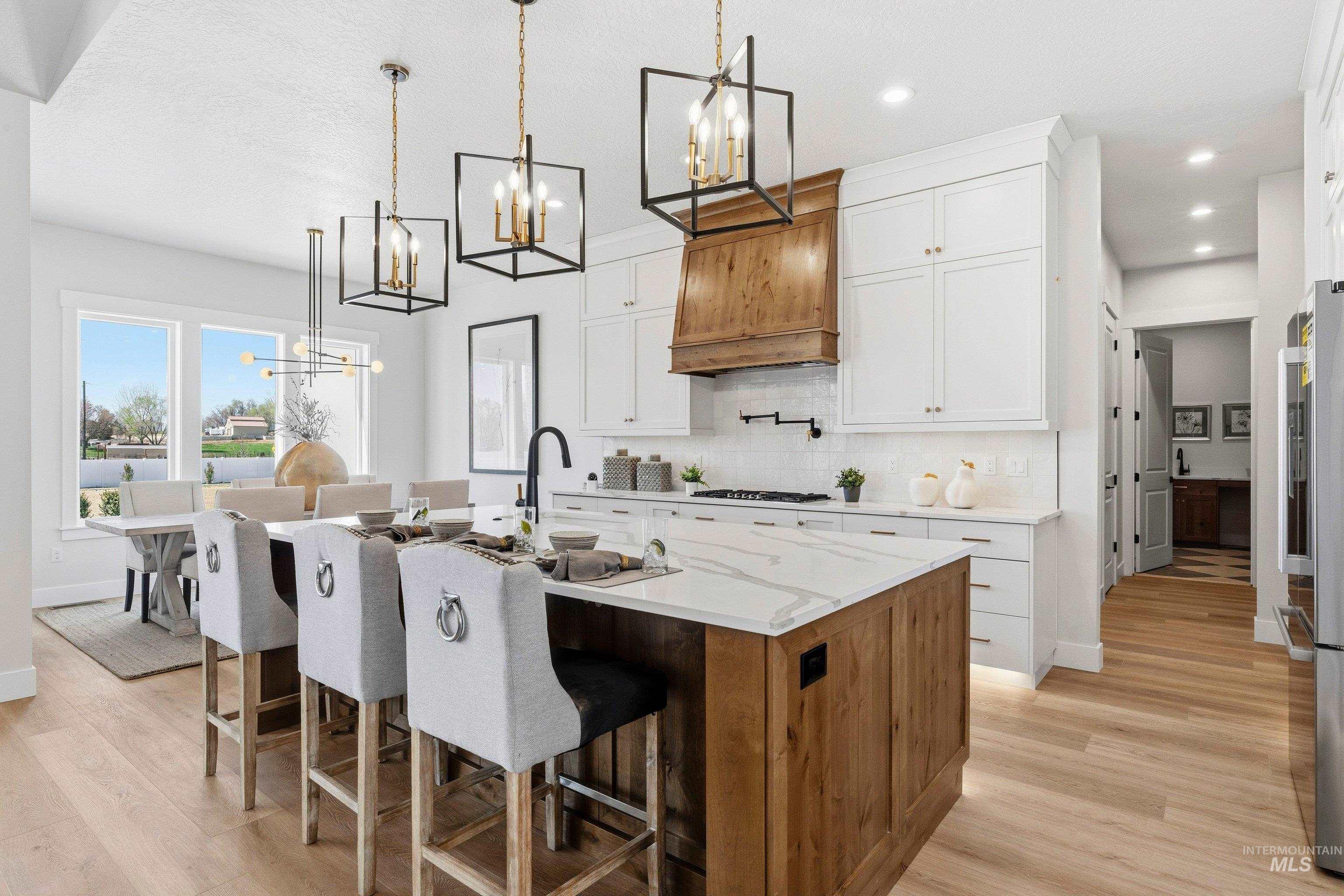 Kitchen with a chandelier, a kitchen bar, two tone color scheme, light stone countertops, and a center island with sink
