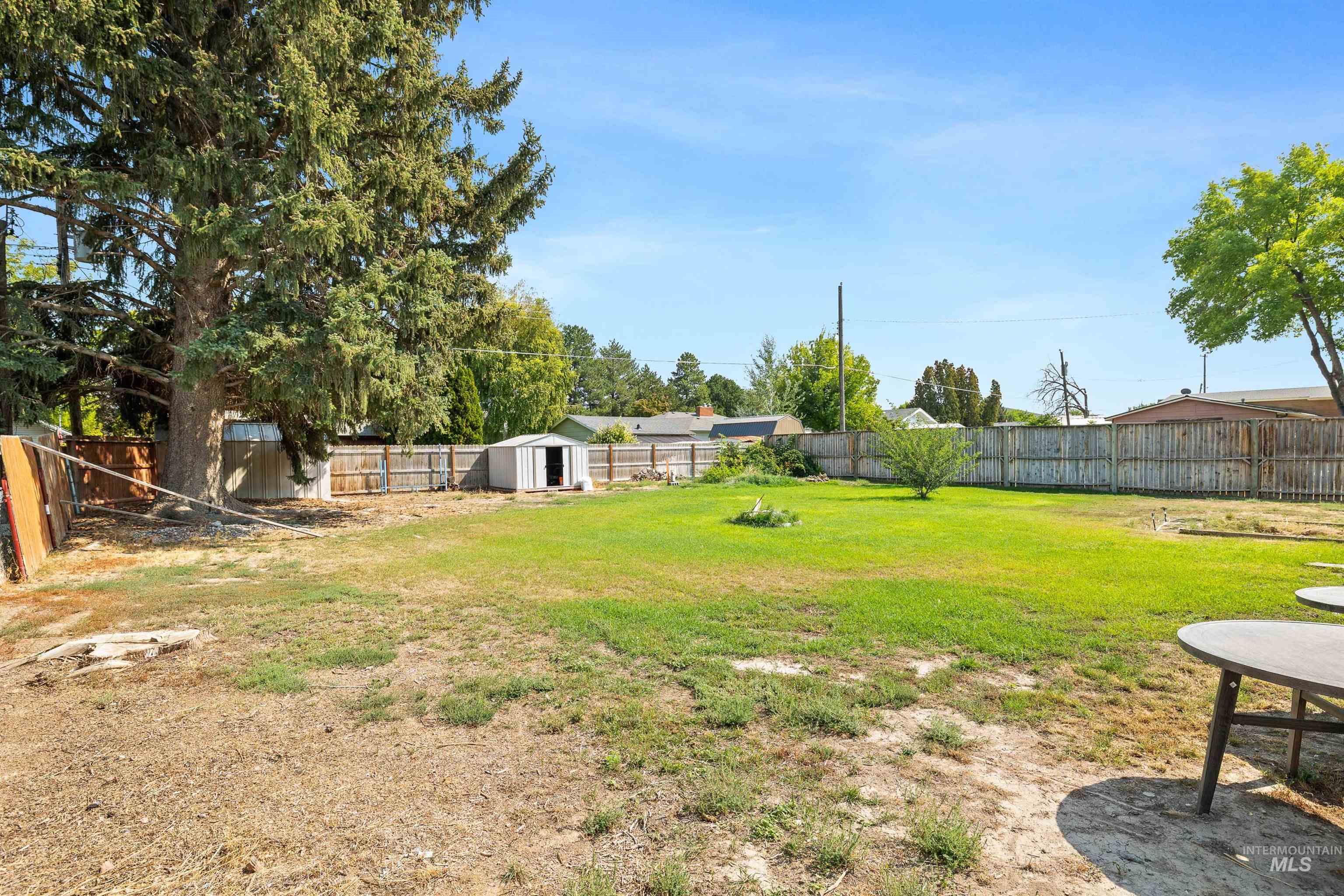 Fenced backyard with a storage unit and a patio area