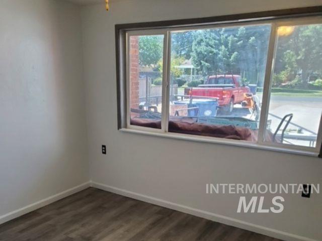 Empty room with baseboards and dark wood-style flooring