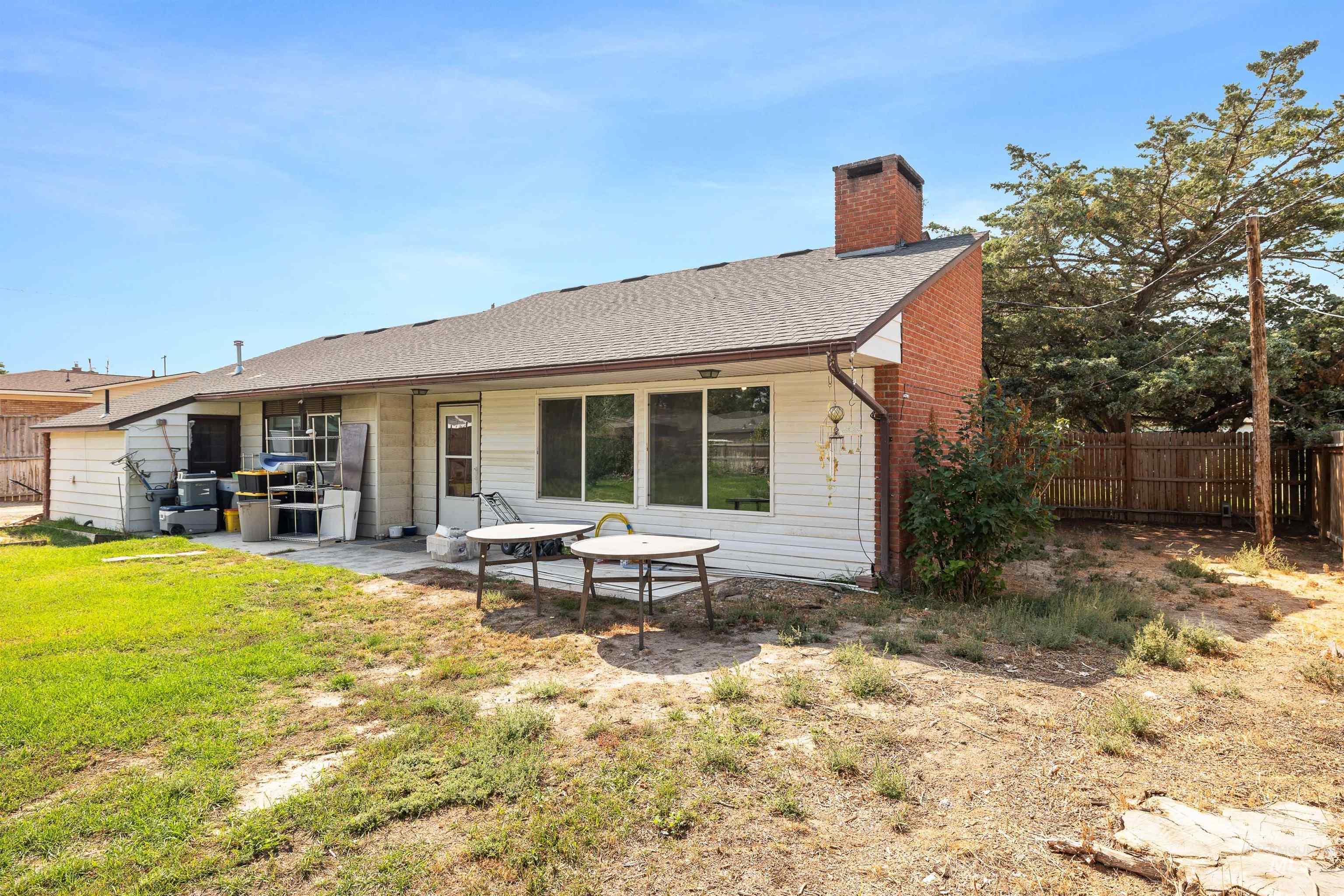 Back of property featuring a patio area, a chimney, and roof with shingles