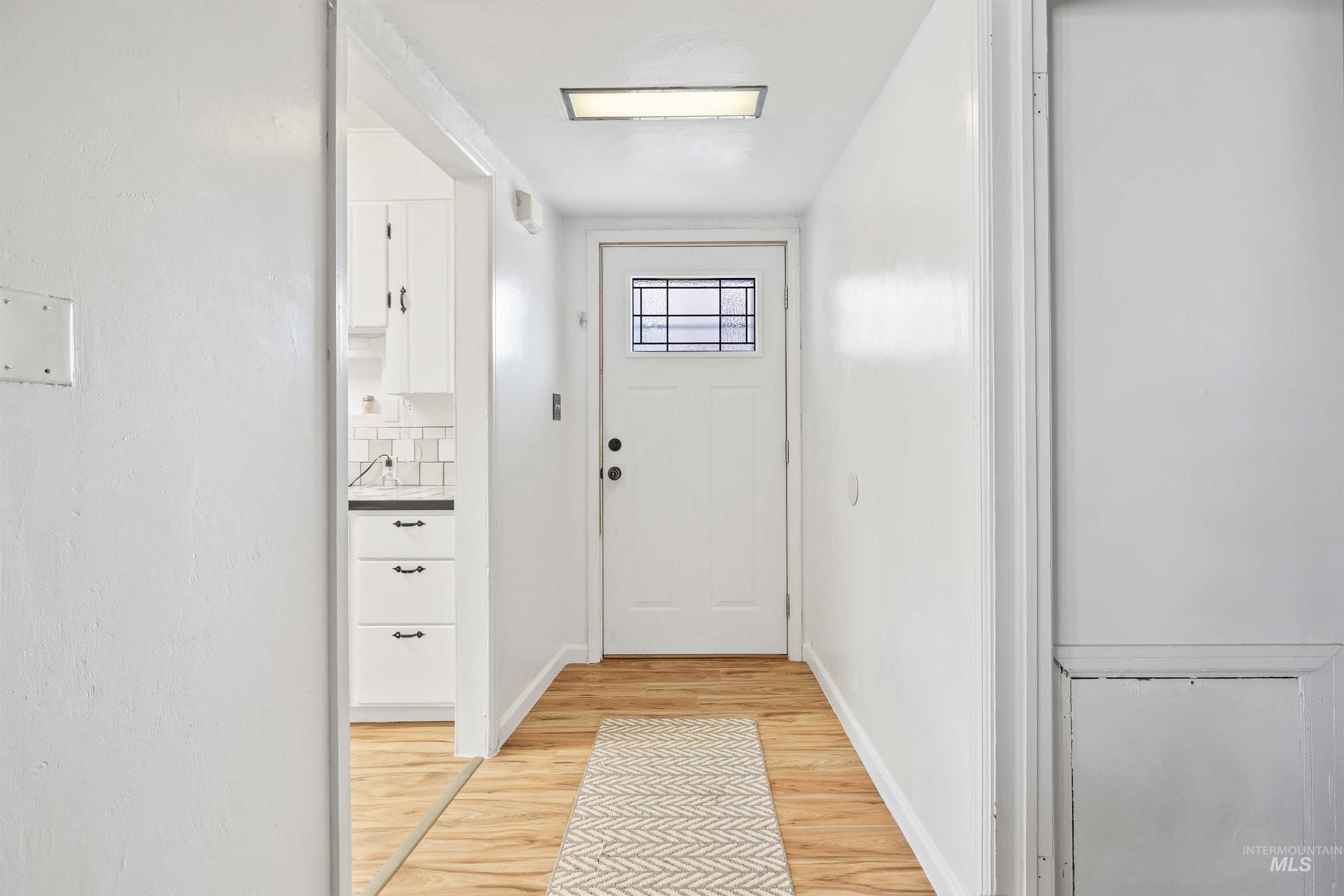 Doorway to outside with wood finished floors and baseboards