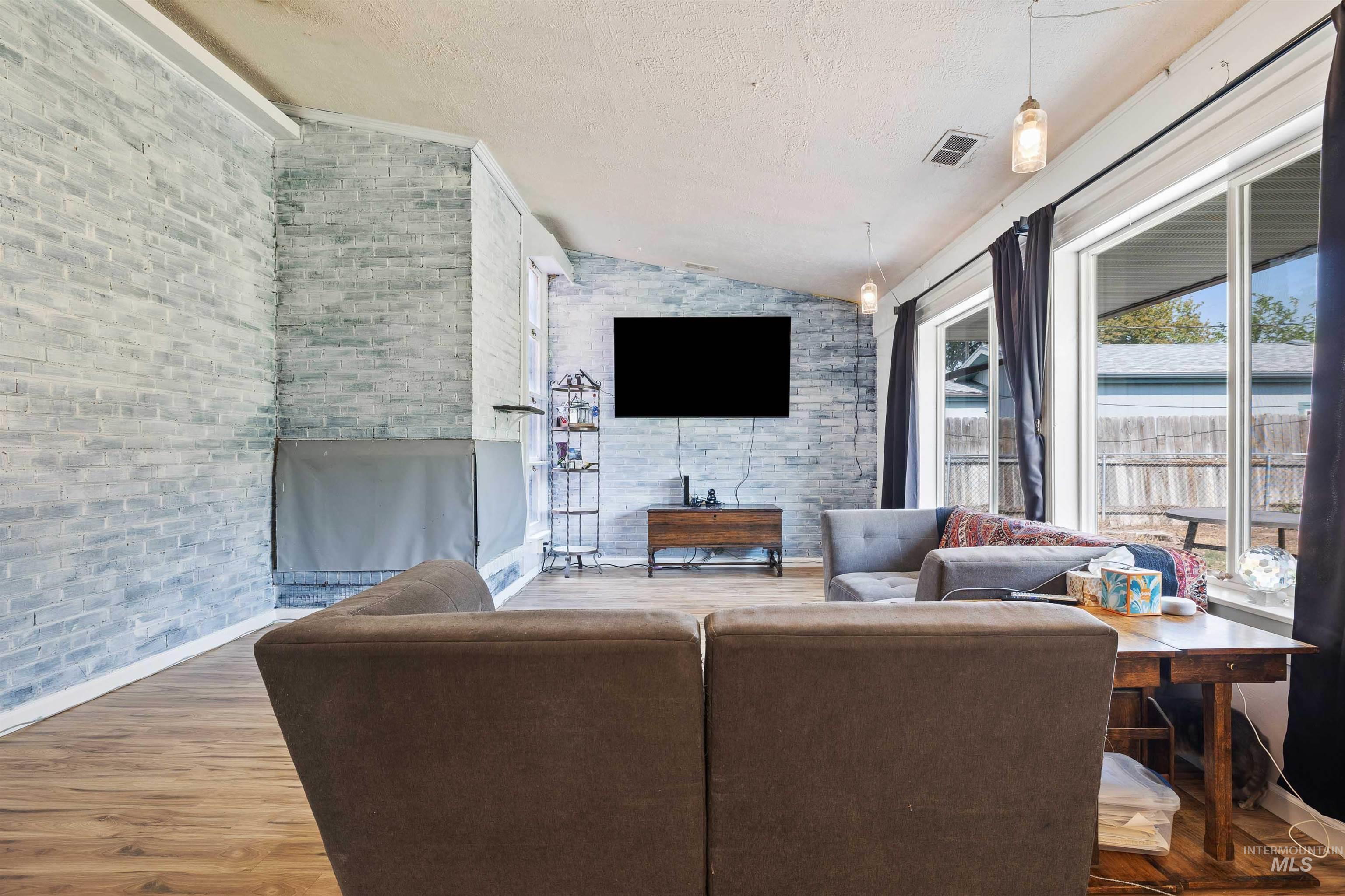 Living area with lofted ceiling, wood finished floors, and a textured ceiling