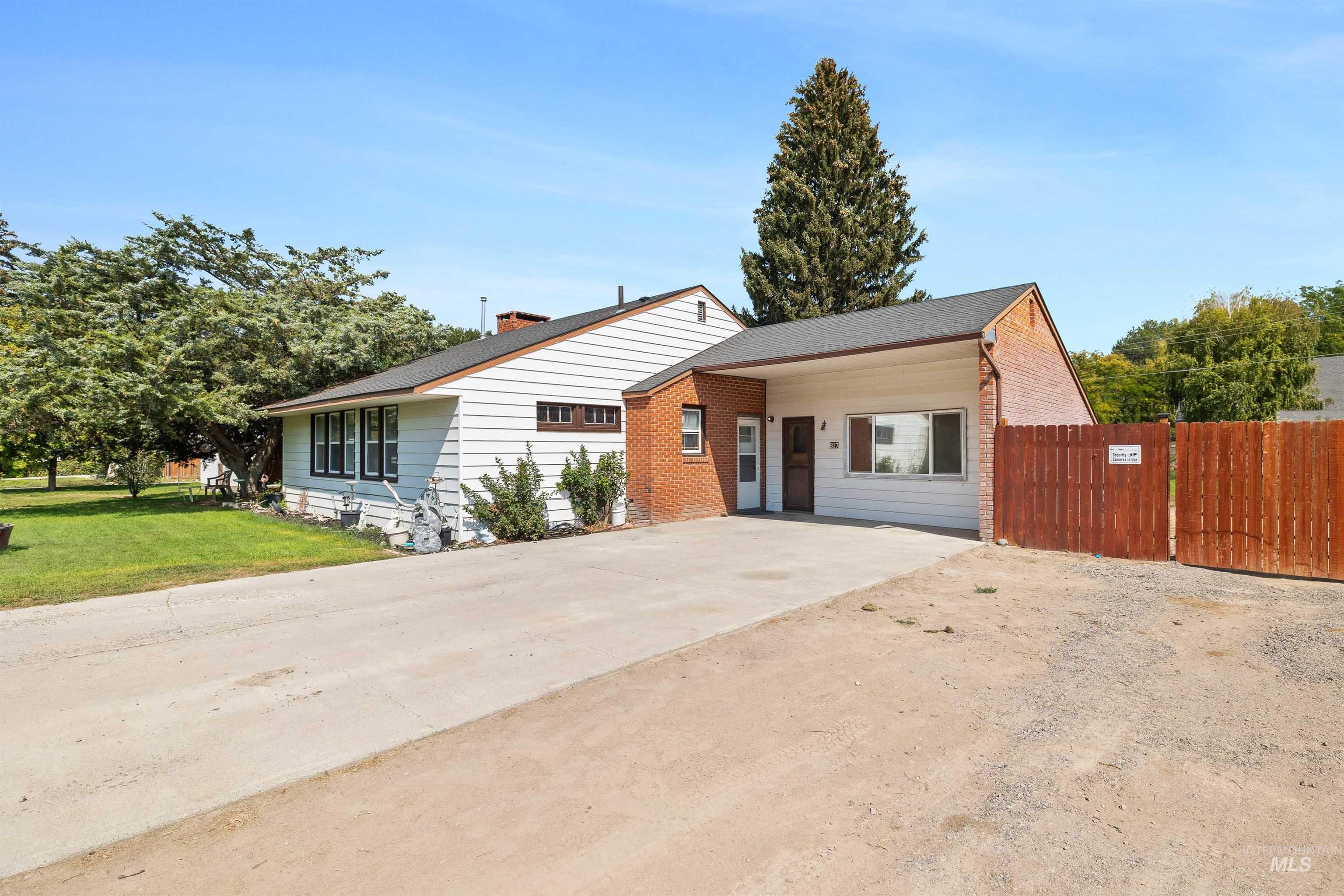 View of front of house with driveway, brick siding, a chimney, and a shingled roof