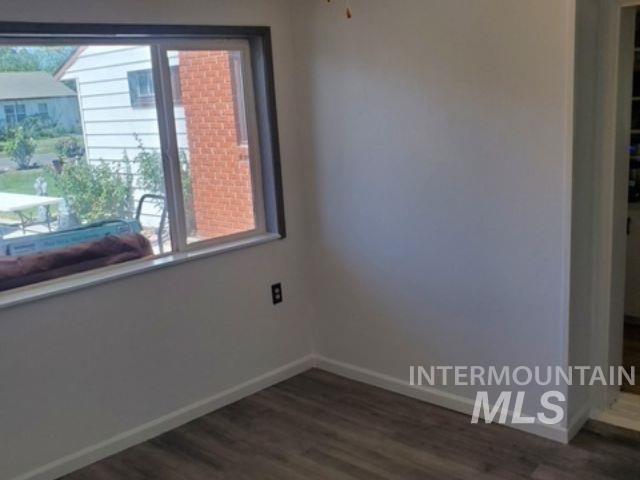 Empty room featuring baseboards and dark wood finished floors