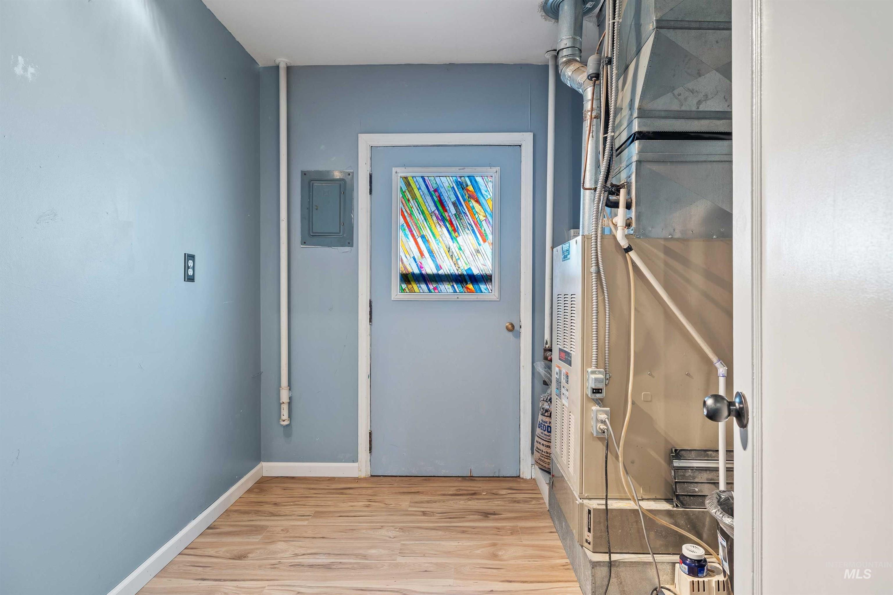 Hallway with light wood-type flooring, heating unit, and electric panel