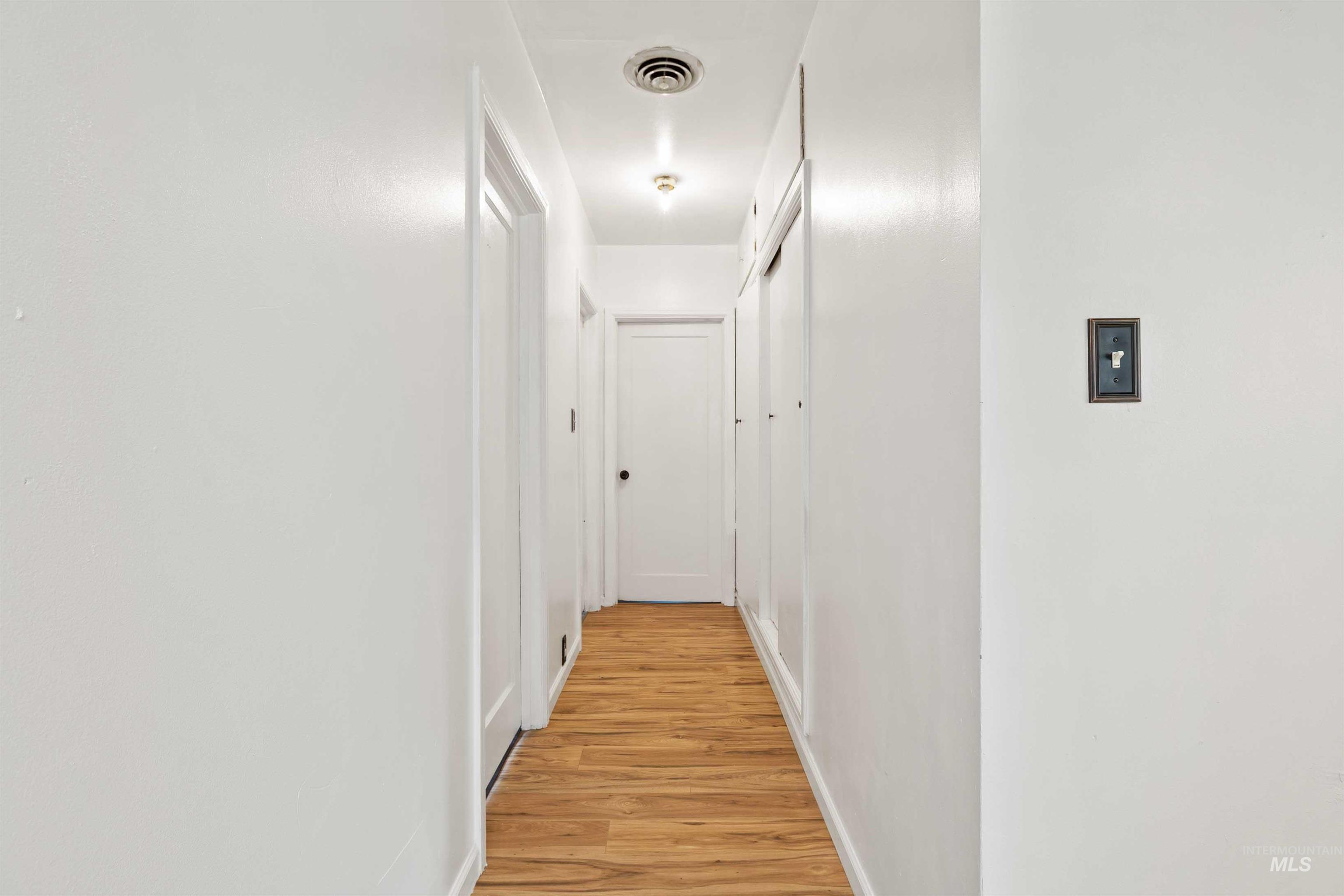 Corridor featuring light wood-style flooring and baseboards