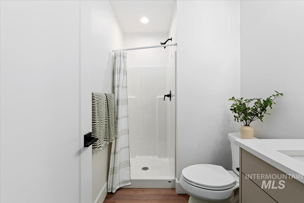 Full bathroom featuring vanity, a shower stall, and wood finished floors