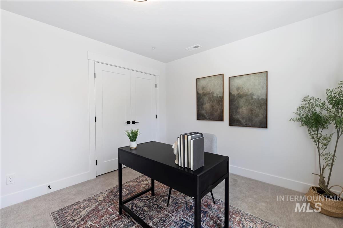 Office area featuring light carpet and baseboards