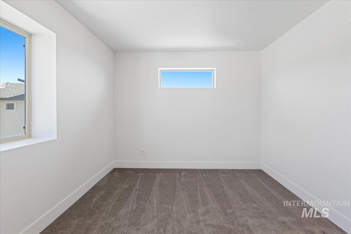 Empty room with dark carpet and baseboards