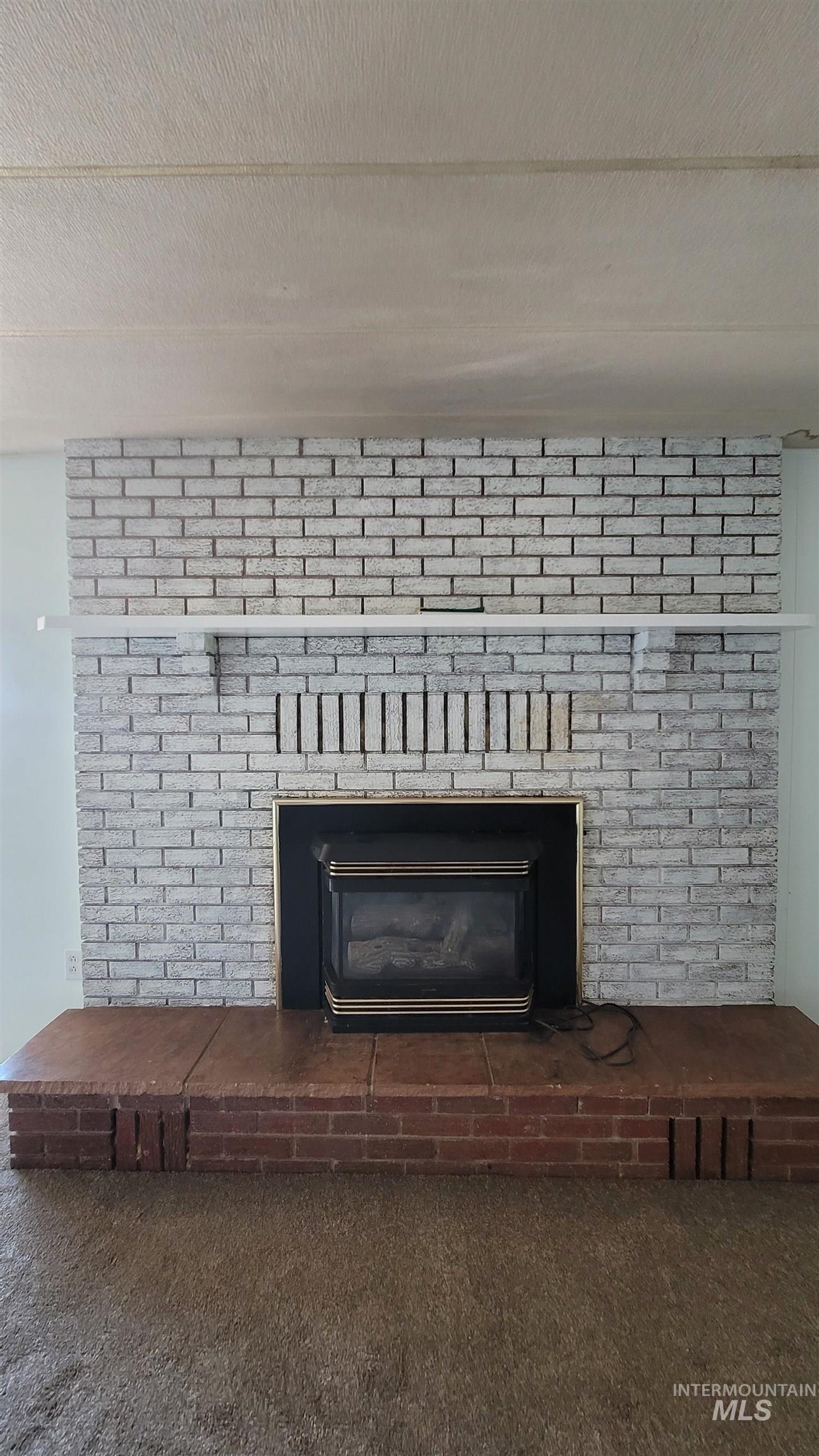 Detailed view of a brick fireplace and carpet flooring