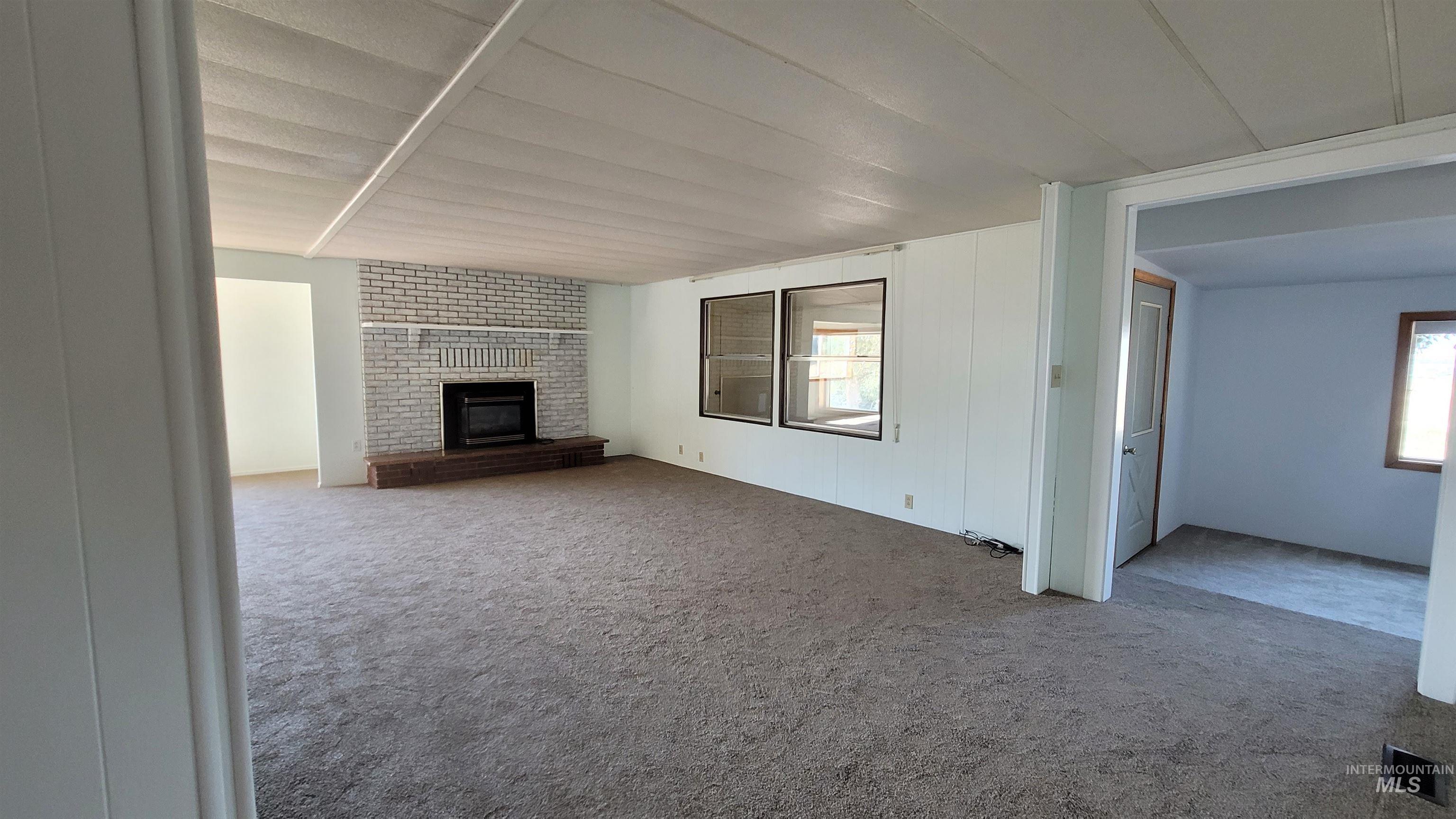Unfurnished living room with carpet flooring and a fireplace