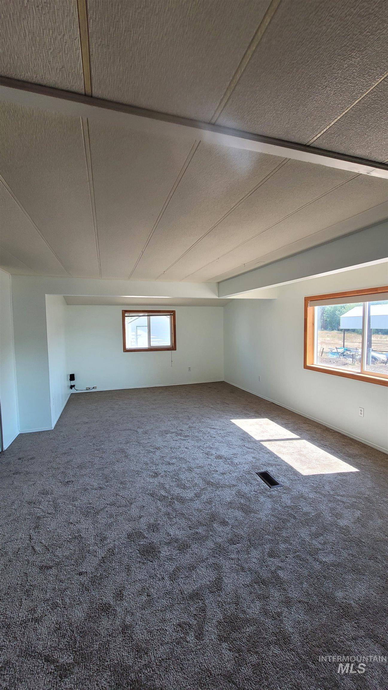 Carpeted empty room featuring healthy amount of natural light and a textured ceiling