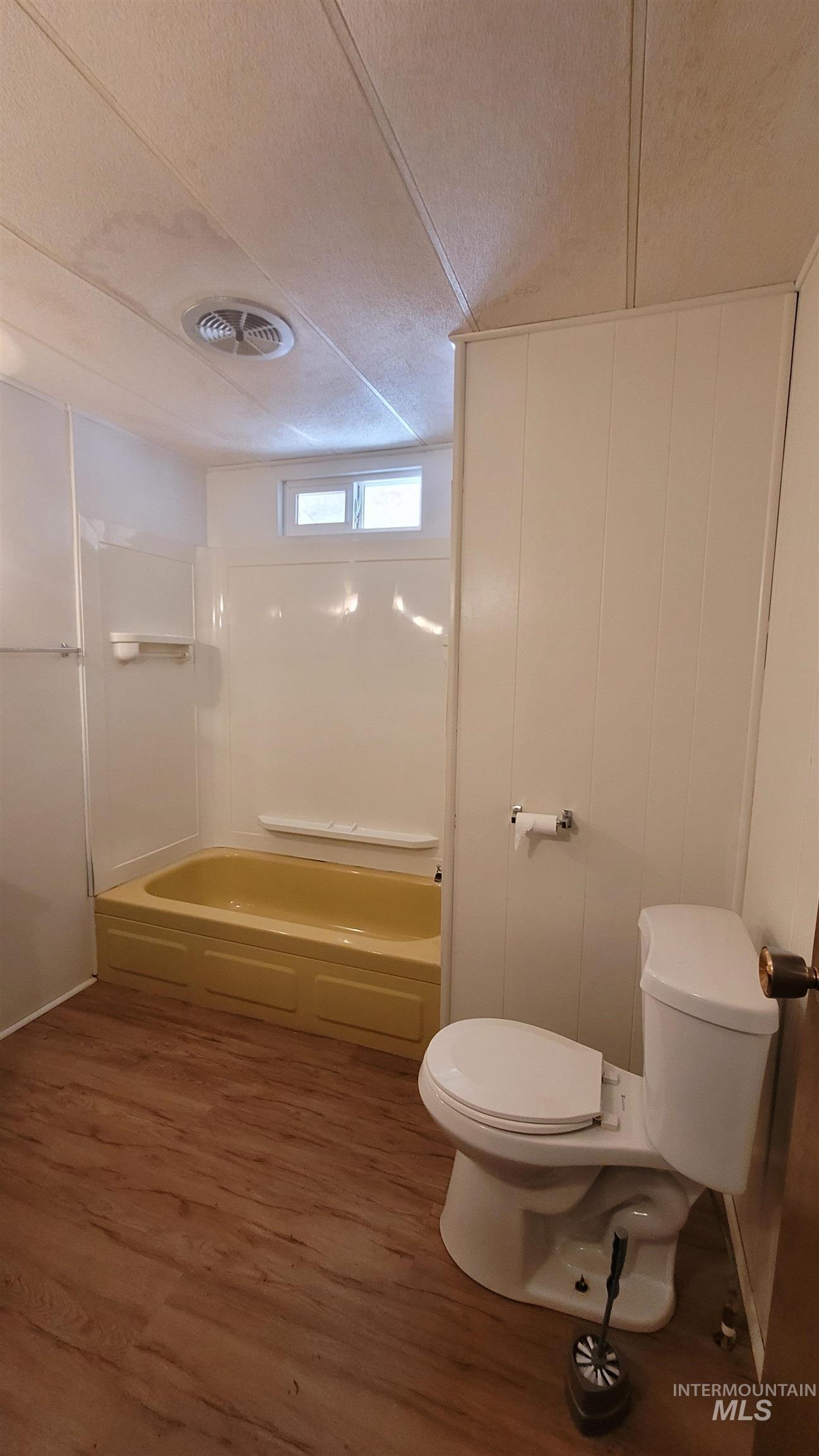 Full bath with dark wood-type flooring, shower / tub combination, and a textured ceiling