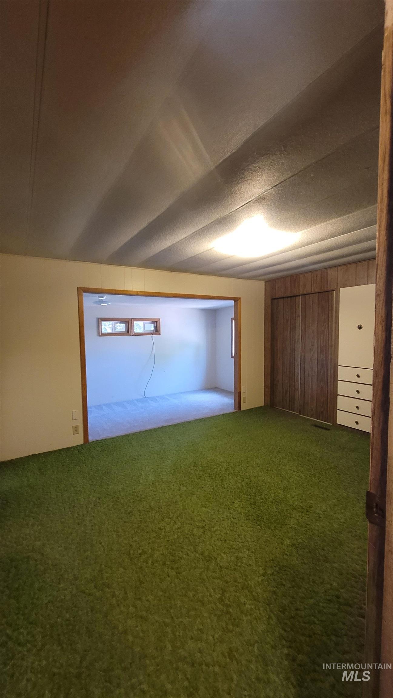 Unfurnished bedroom featuring carpet and wood walls