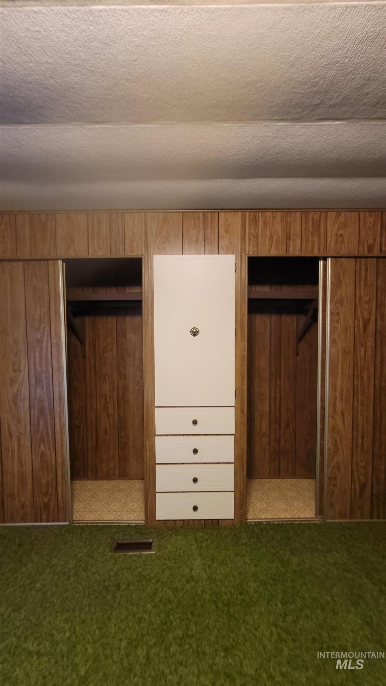 Unfurnished bedroom featuring a textured ceiling, carpet floors, and multiple closets