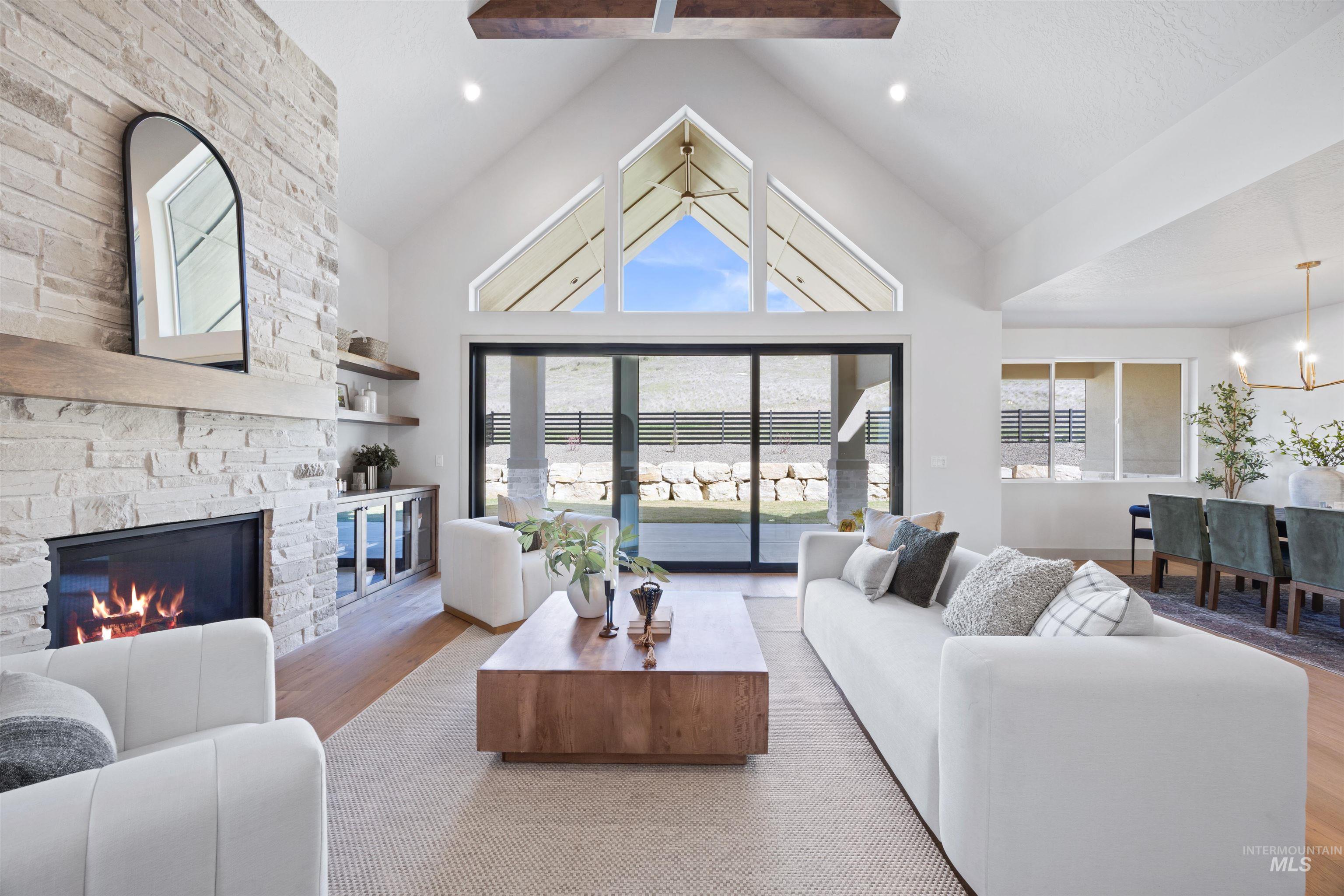 Living room featuring wood finished floors, a stone fireplace, a chandelier, and a high ceiling
