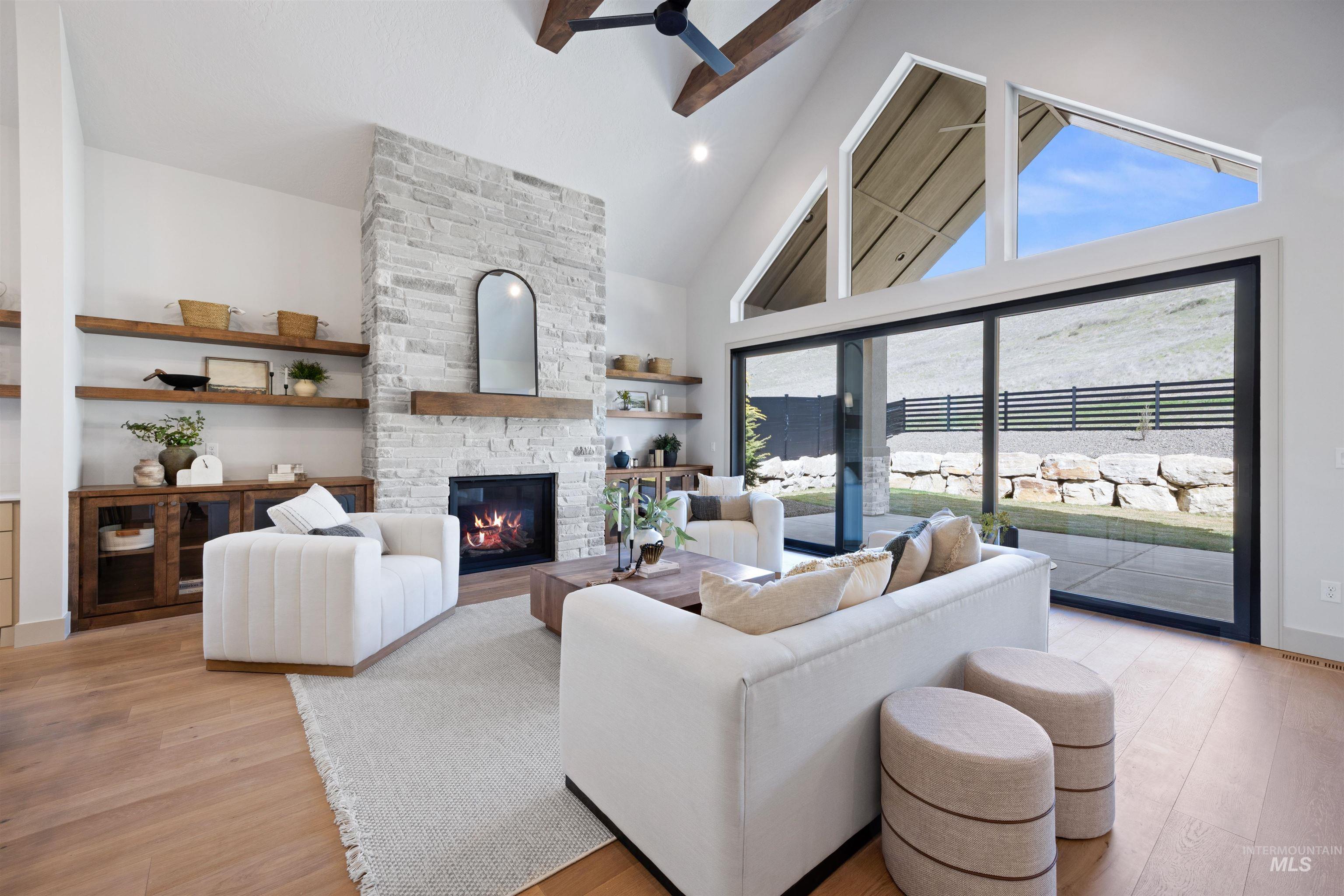 Living room with light wood-style floors, ceiling fan, vaulted ceiling, a stone fireplace, and recessed lighting