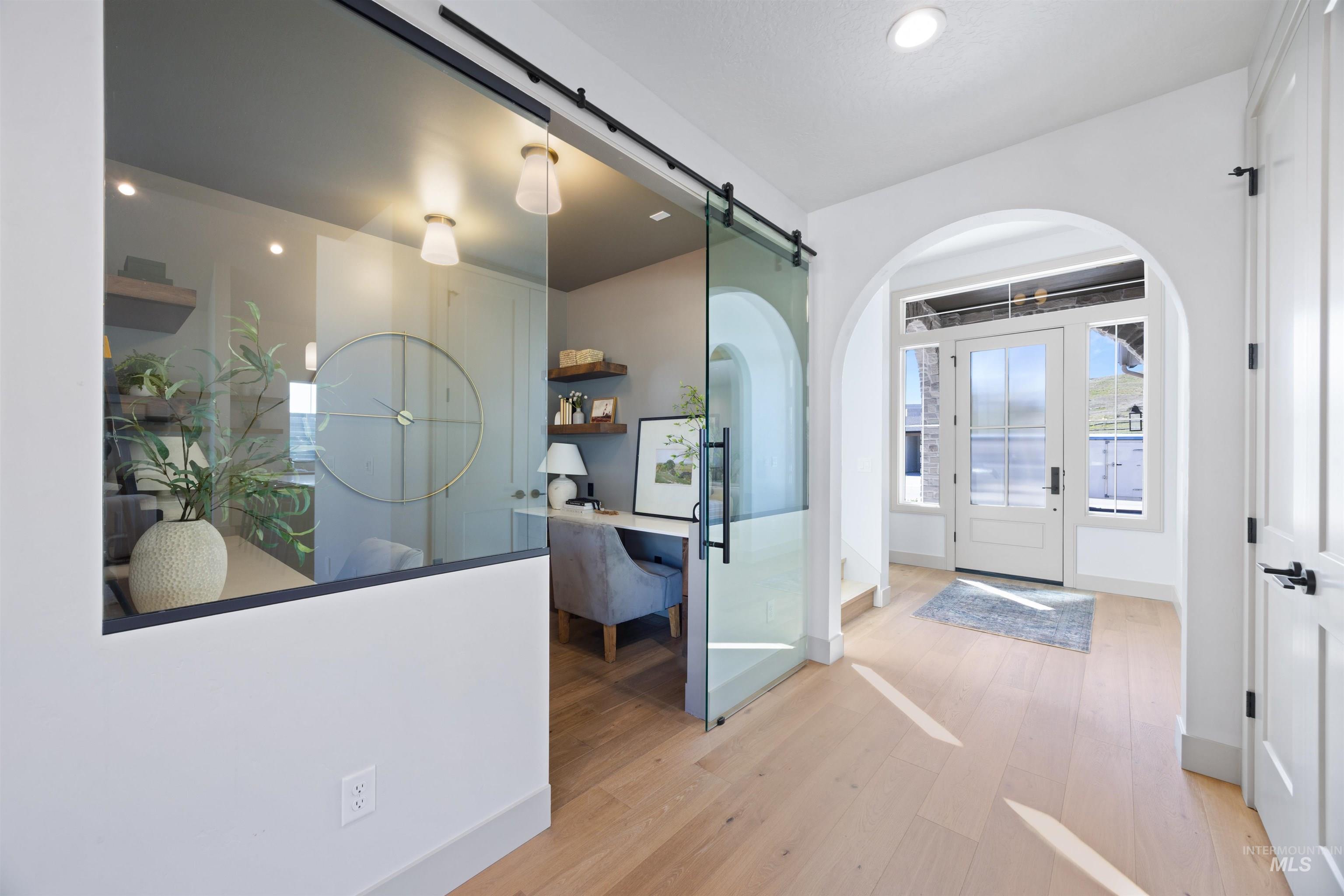 Foyer entrance featuring arched walkways, light wood finished floors, a barn door, and recessed lighting