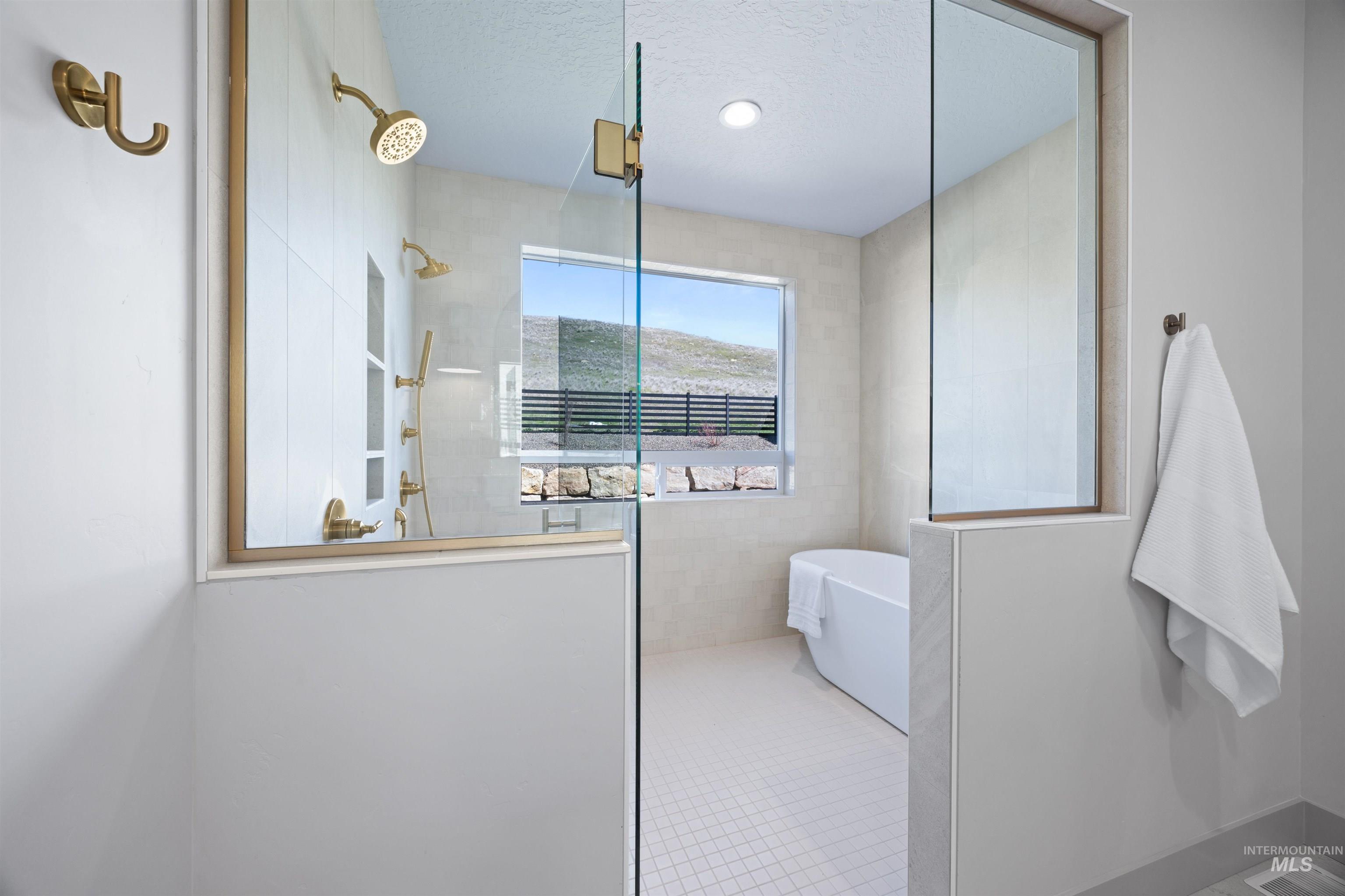 Full bath featuring a walk in shower, a soaking tub, a textured ceiling, and light tile patterned flooring