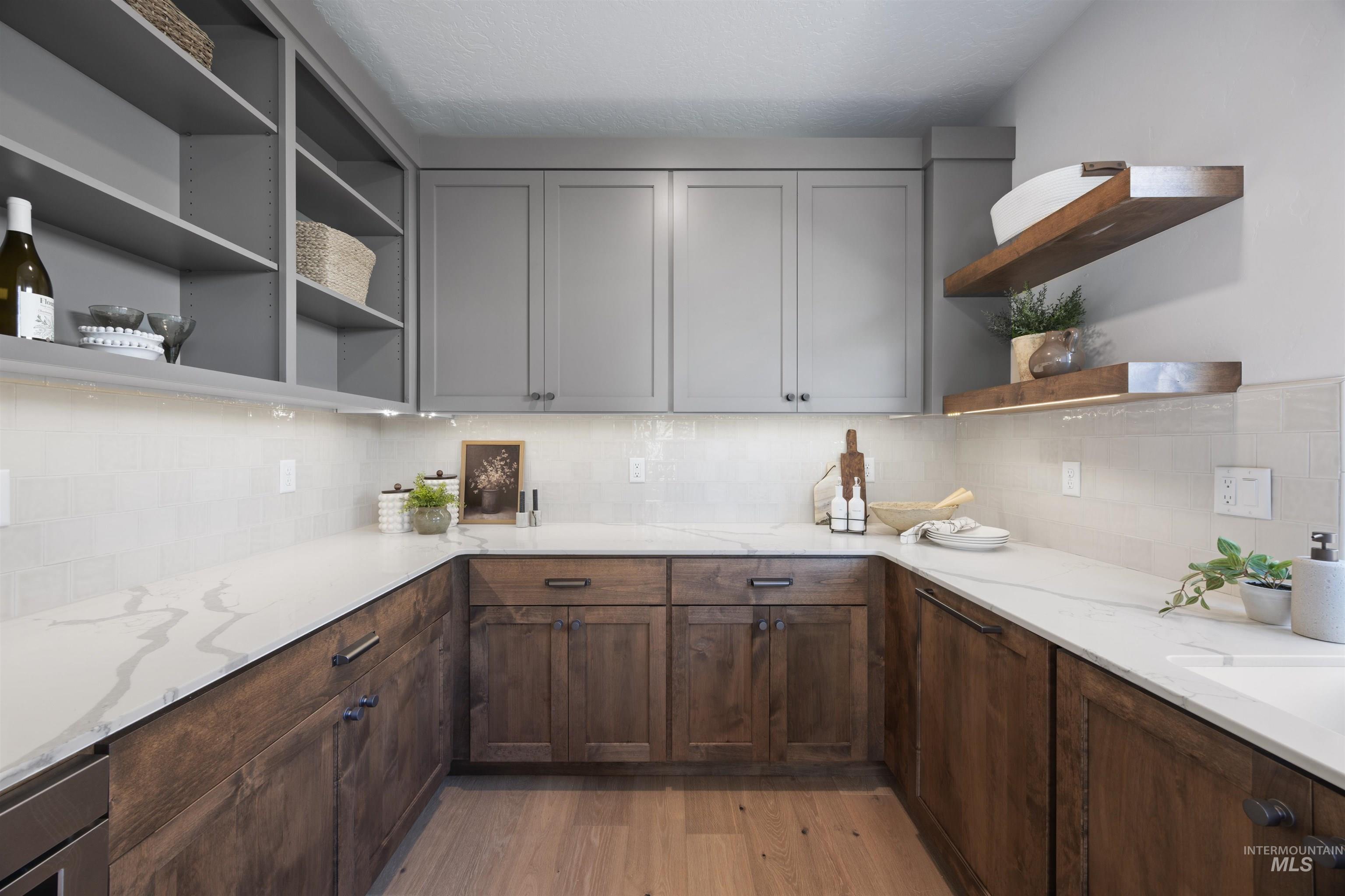 Kitchen featuring open shelves, backsplash, light wood finished floors, and light stone countertops