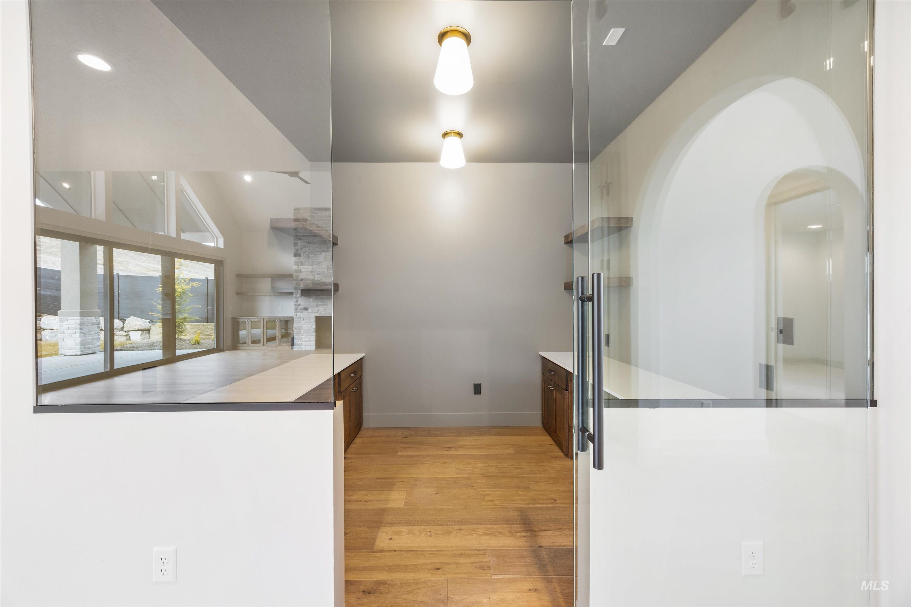 Kitchen with light wood-style flooring, arched walkways, recessed lighting, vaulted ceiling, and dark wood finish cabinetry