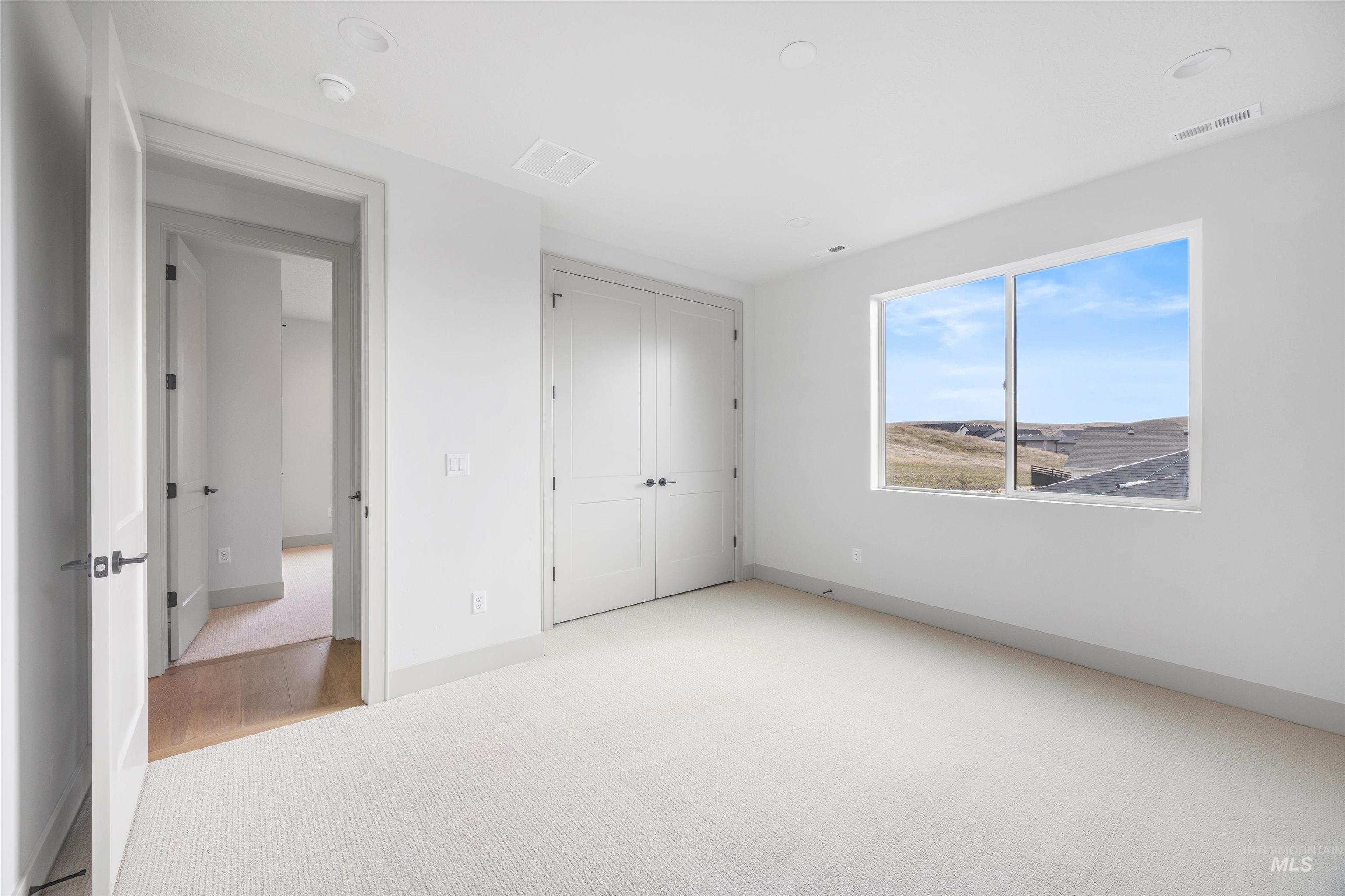 Unfurnished bedroom featuring light carpet and a closet