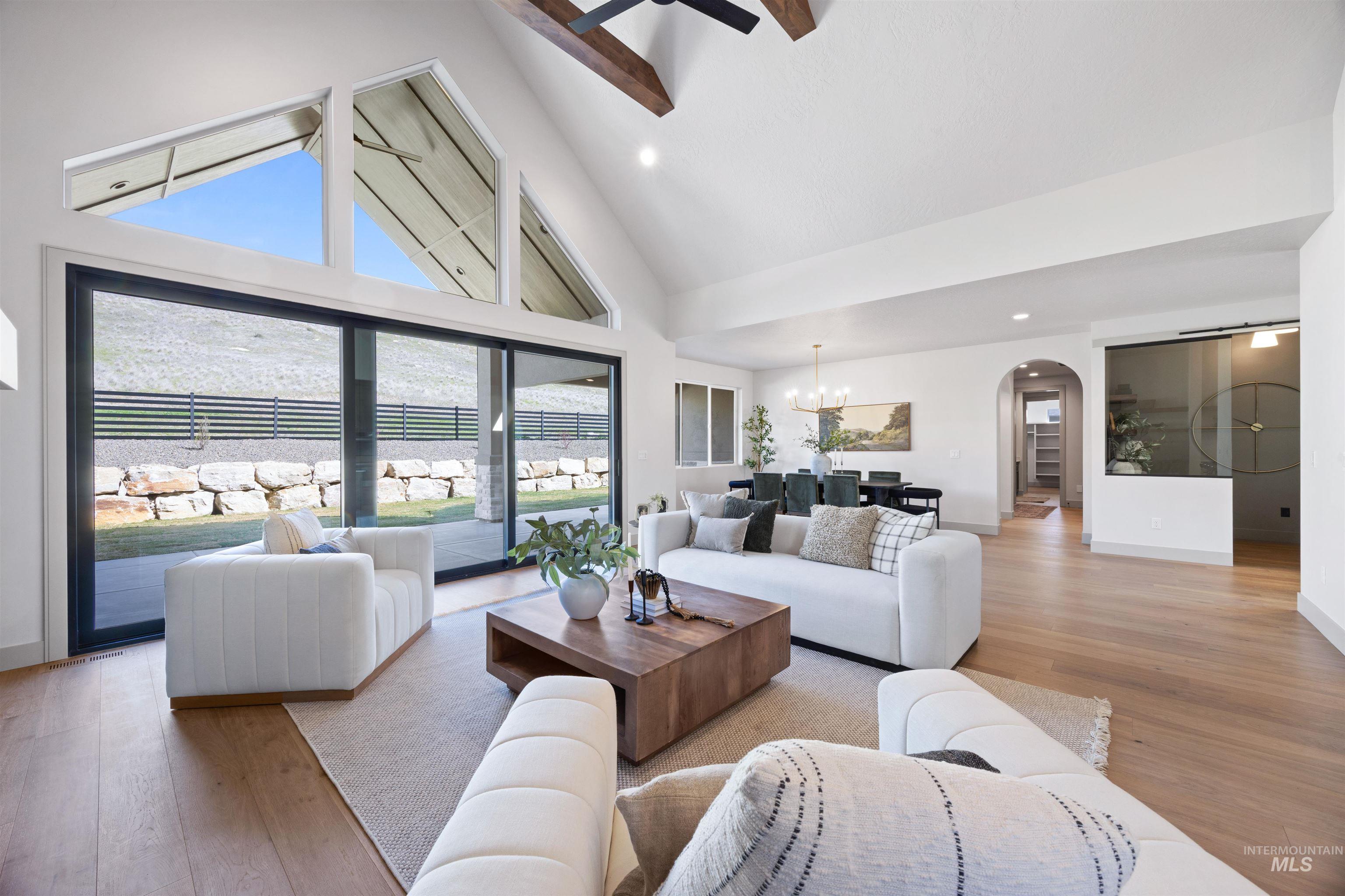 Living area with light wood-type flooring, arched walkways, lofted ceiling, ceiling fan, and hanging lights