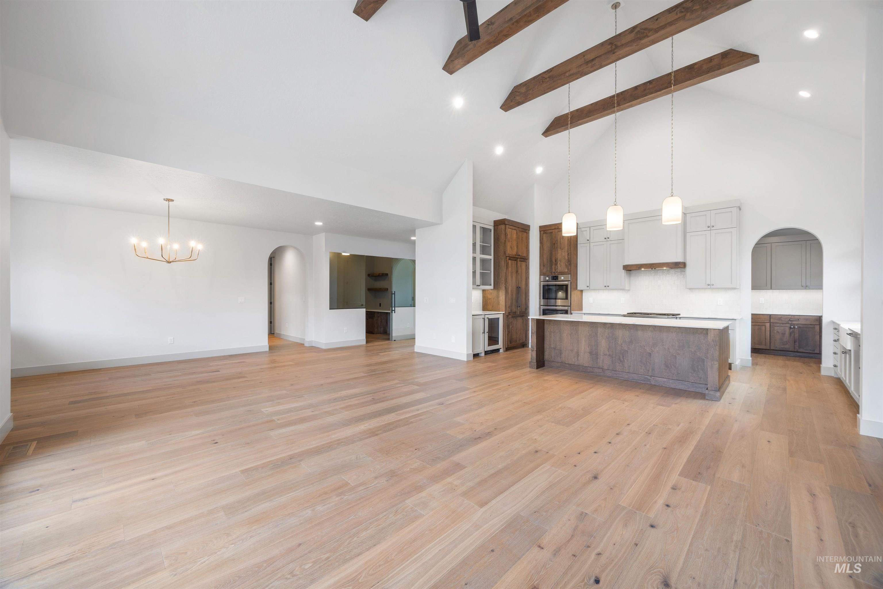 Two tone kitchen with arched walkways, open floor plan, light countertops, a spacious island, and two tone cabinets