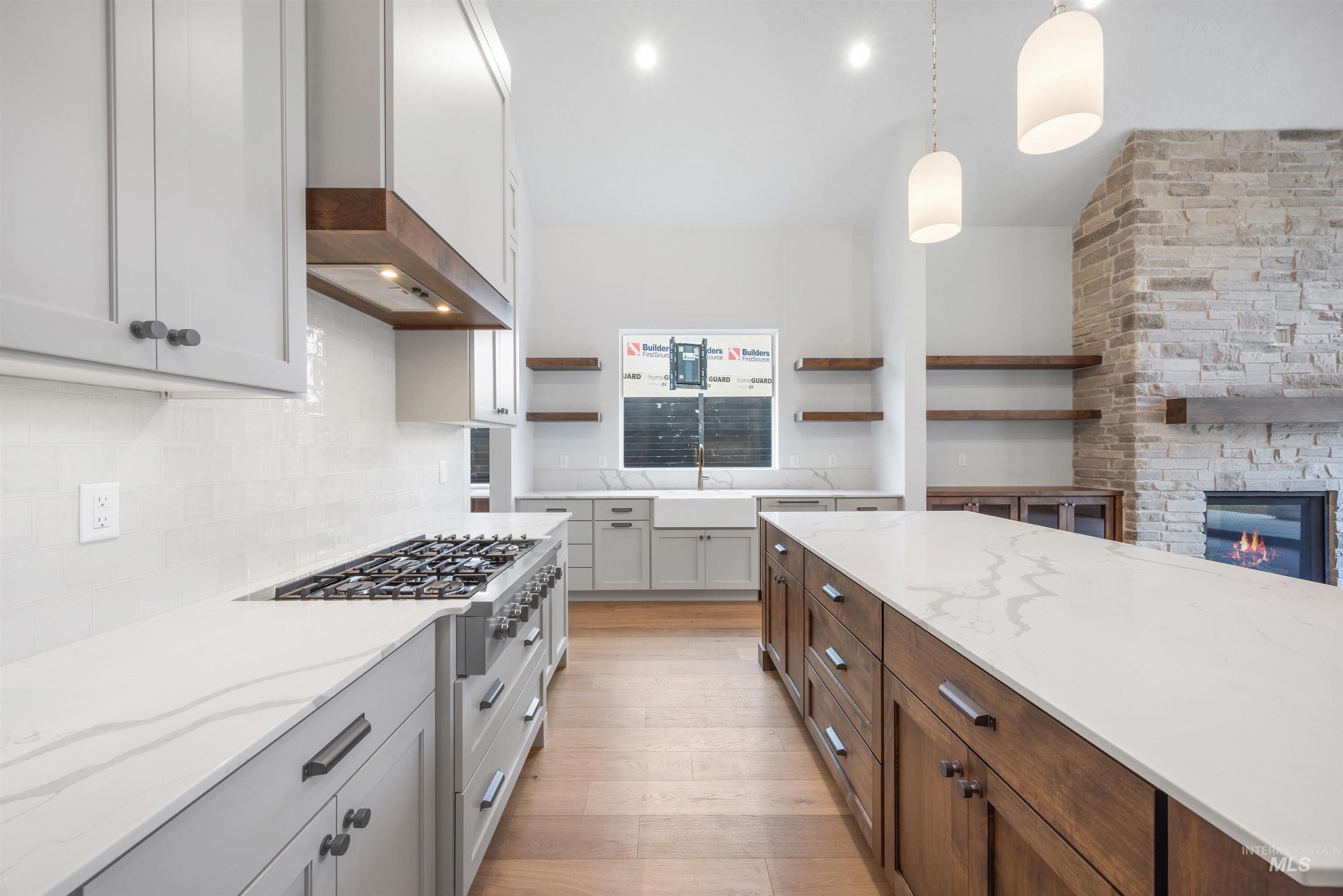 Kitchen featuring light stone countertops, hanging light fixtures, a fireplace, dual tone cabinetry, and open shelves