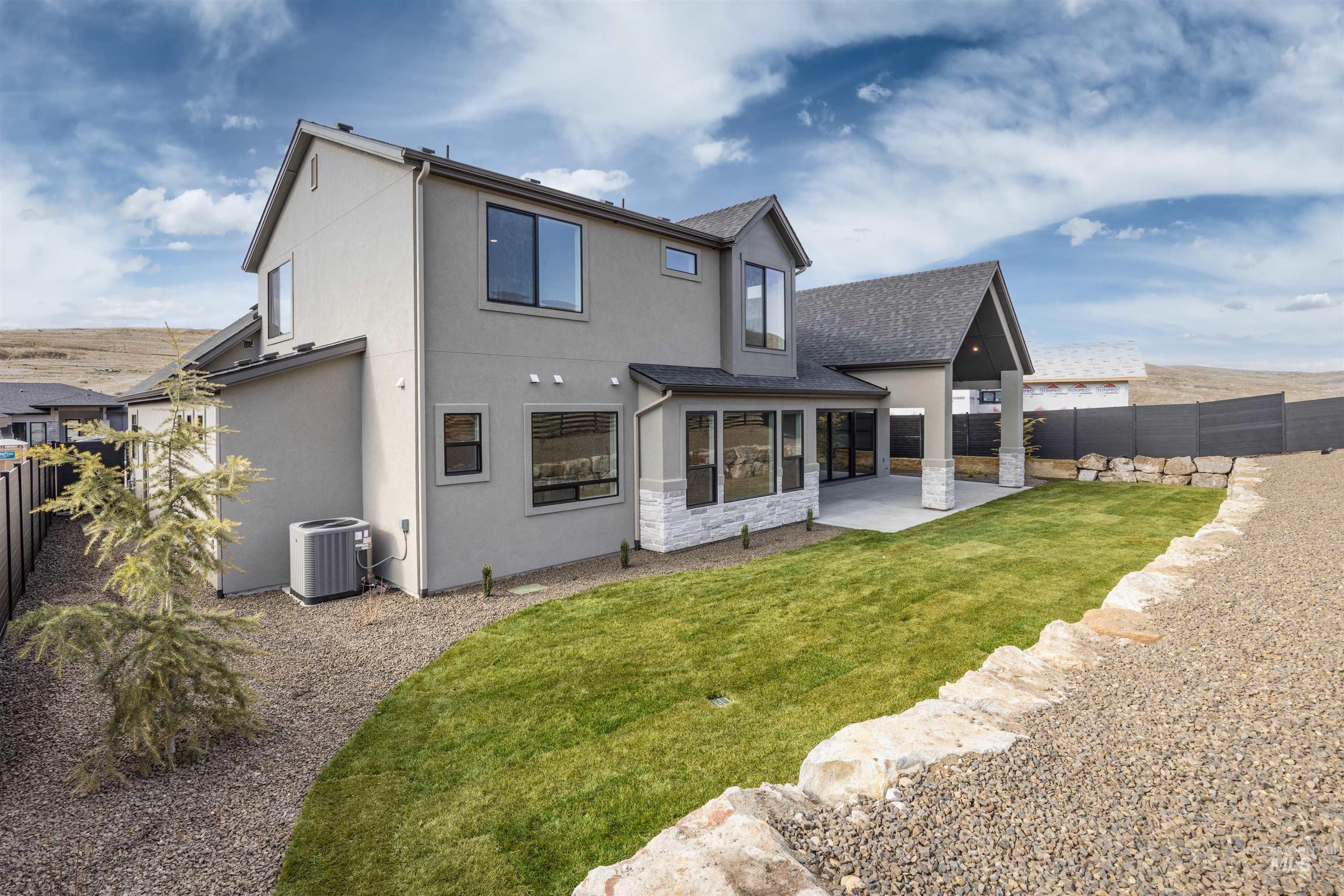 Rear view of property featuring a fenced backyard, a patio area, stucco siding, stone siding, and a shingled roof