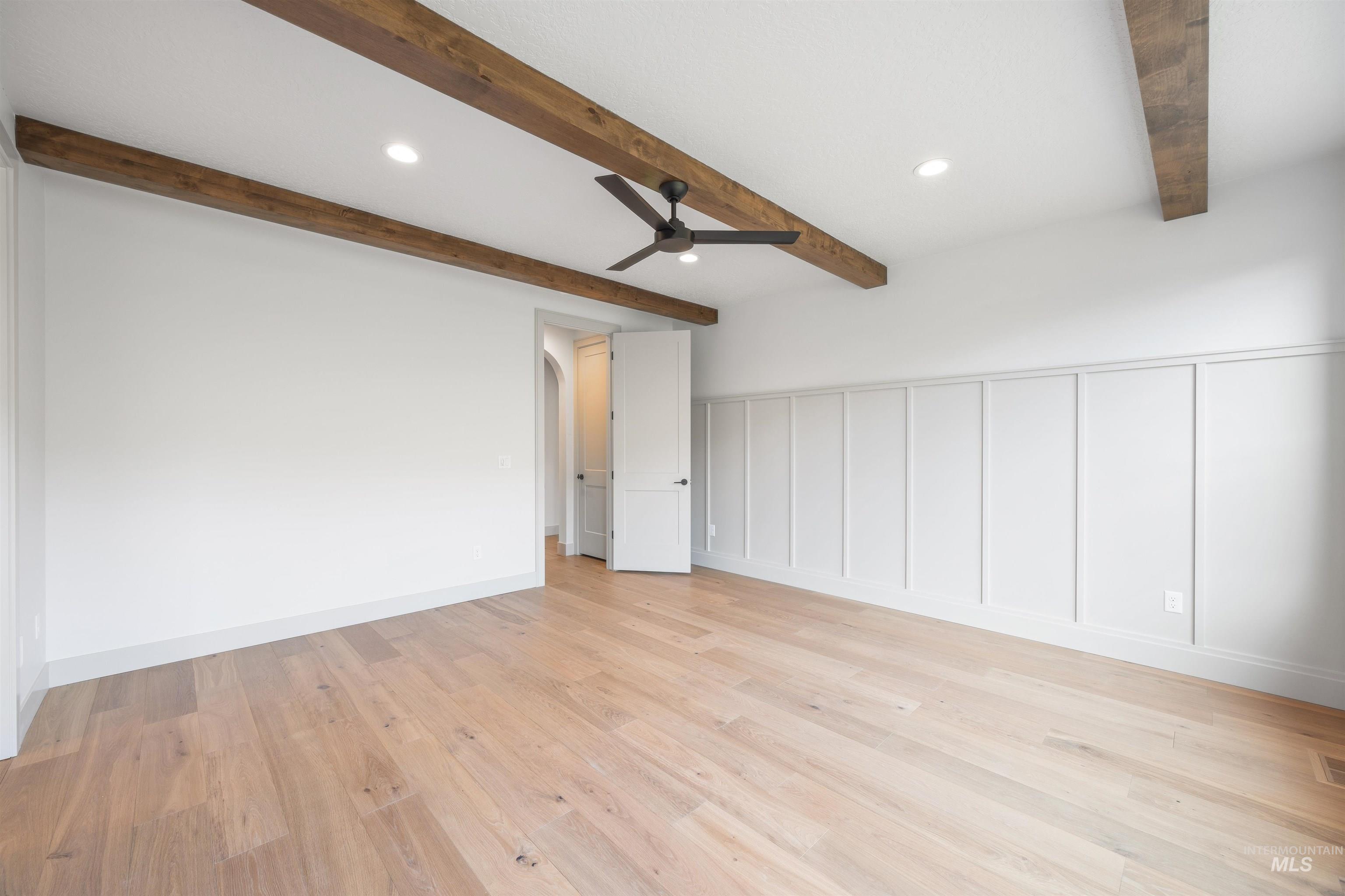 Empty room featuring a decorative wall, recessed lighting, a ceiling fan, light wood-type flooring, and arched walkways