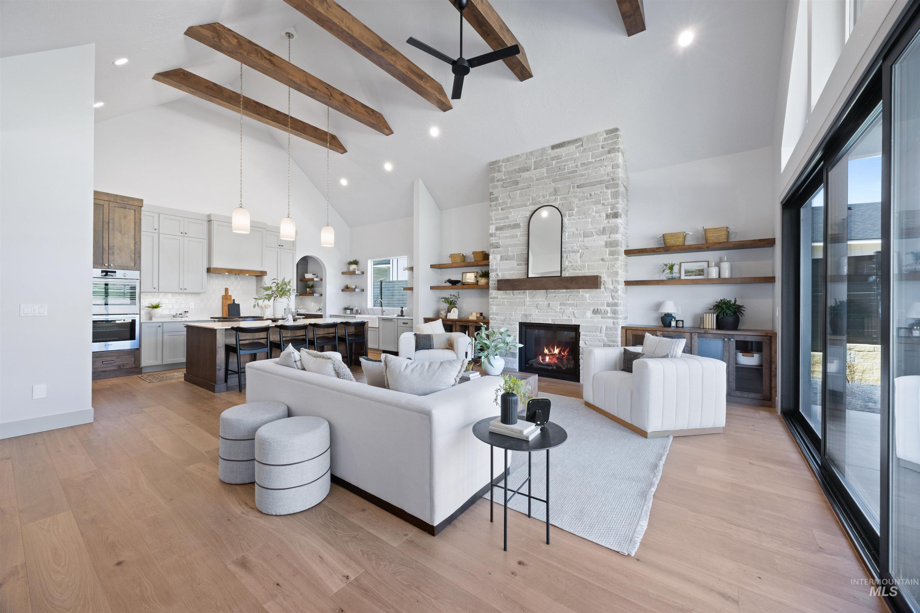 Living area with a stone fireplace, a ceiling fan, light wood-type flooring, recessed lighting, and lofted ceiling
