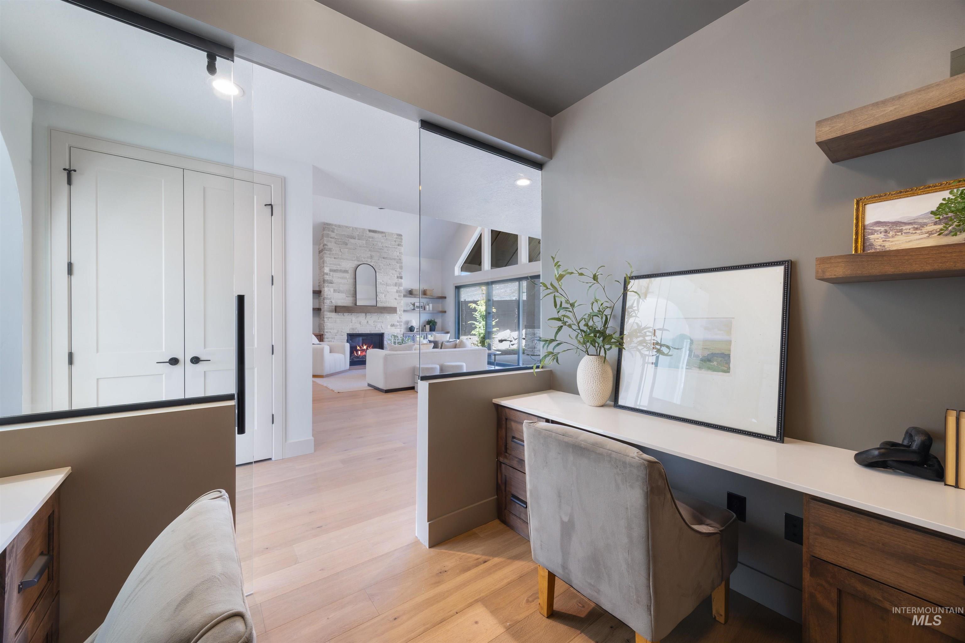 Office with built in desk, light wood-type flooring, a fireplace, and lofted ceiling