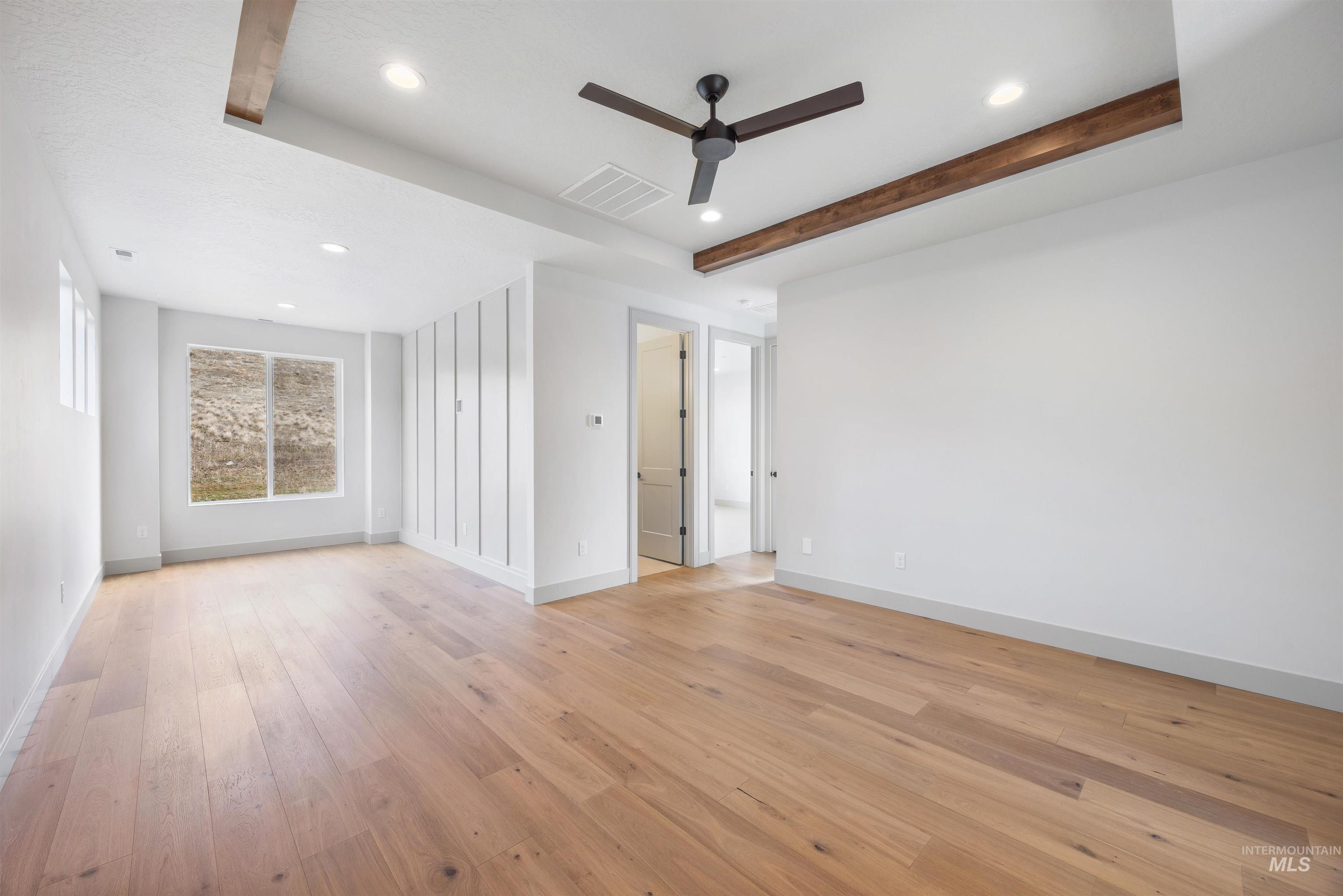 Empty room with a ceiling fan, beamed ceiling, recessed lighting, and light wood-style floors