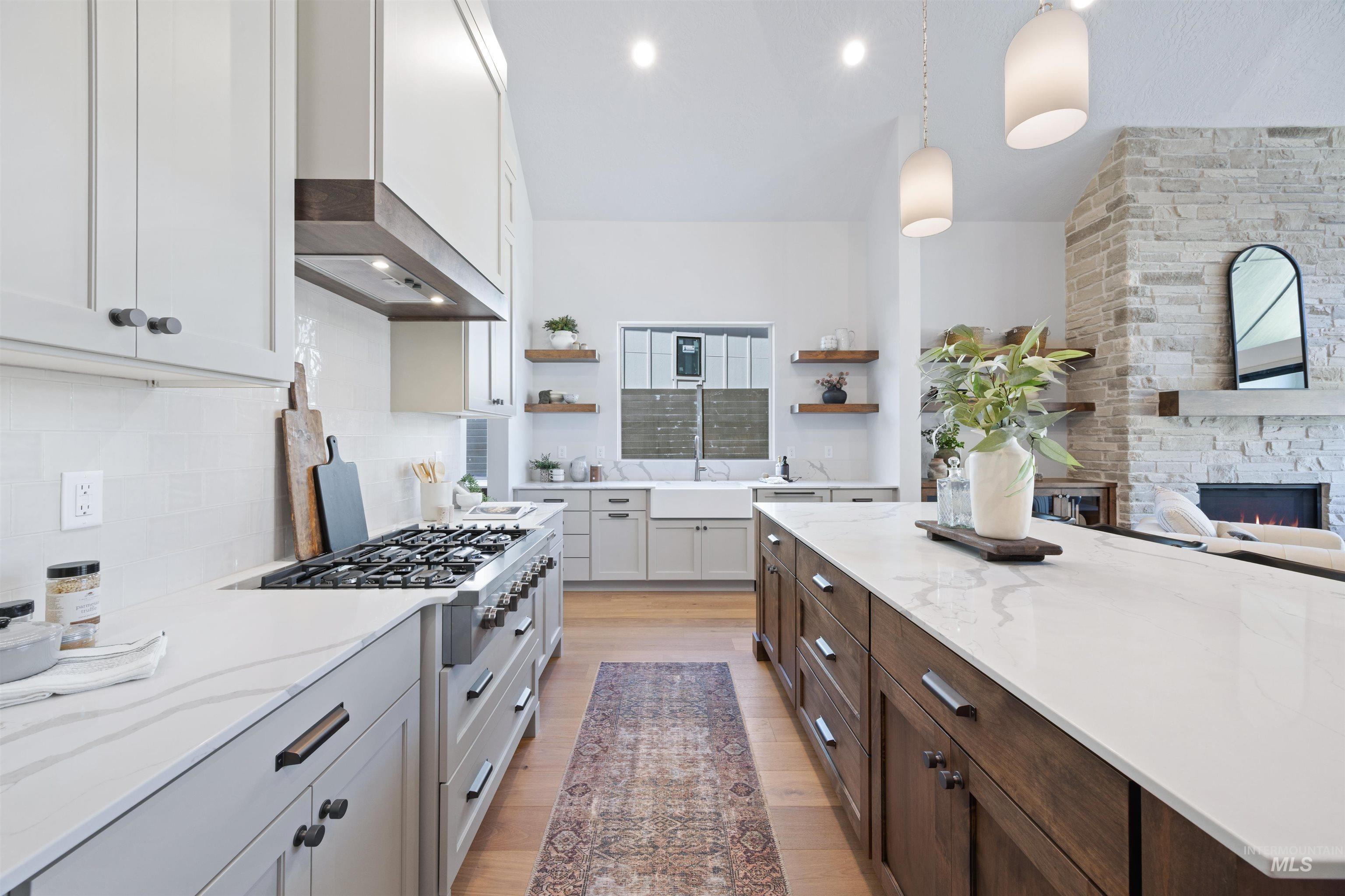 Dual tone kitchen with two tone cabinets, open shelves, light stone countertops, a fireplace, and decorative light fixtures