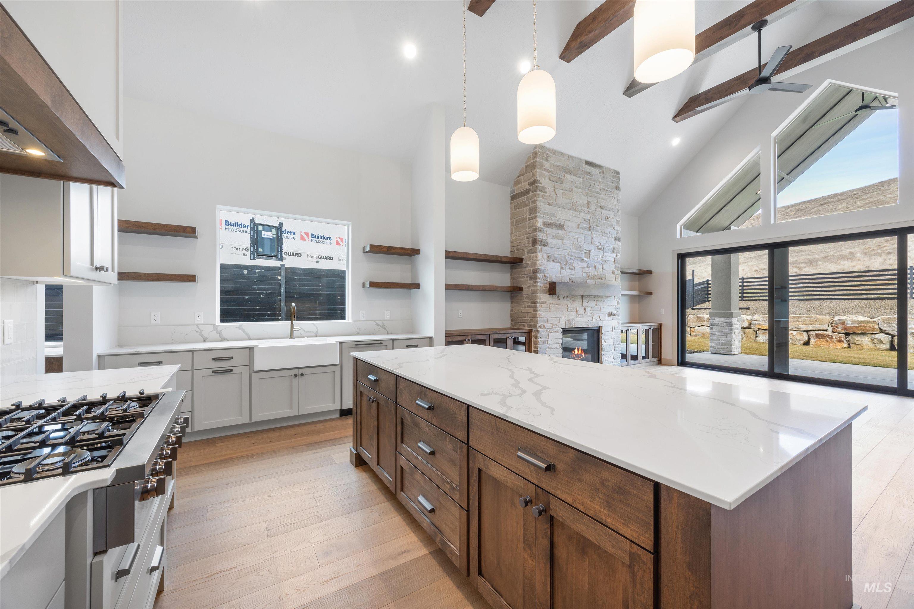 Kitchen featuring open shelves, a fireplace, dual tone cabinetry, decorative light fixtures, and range hood