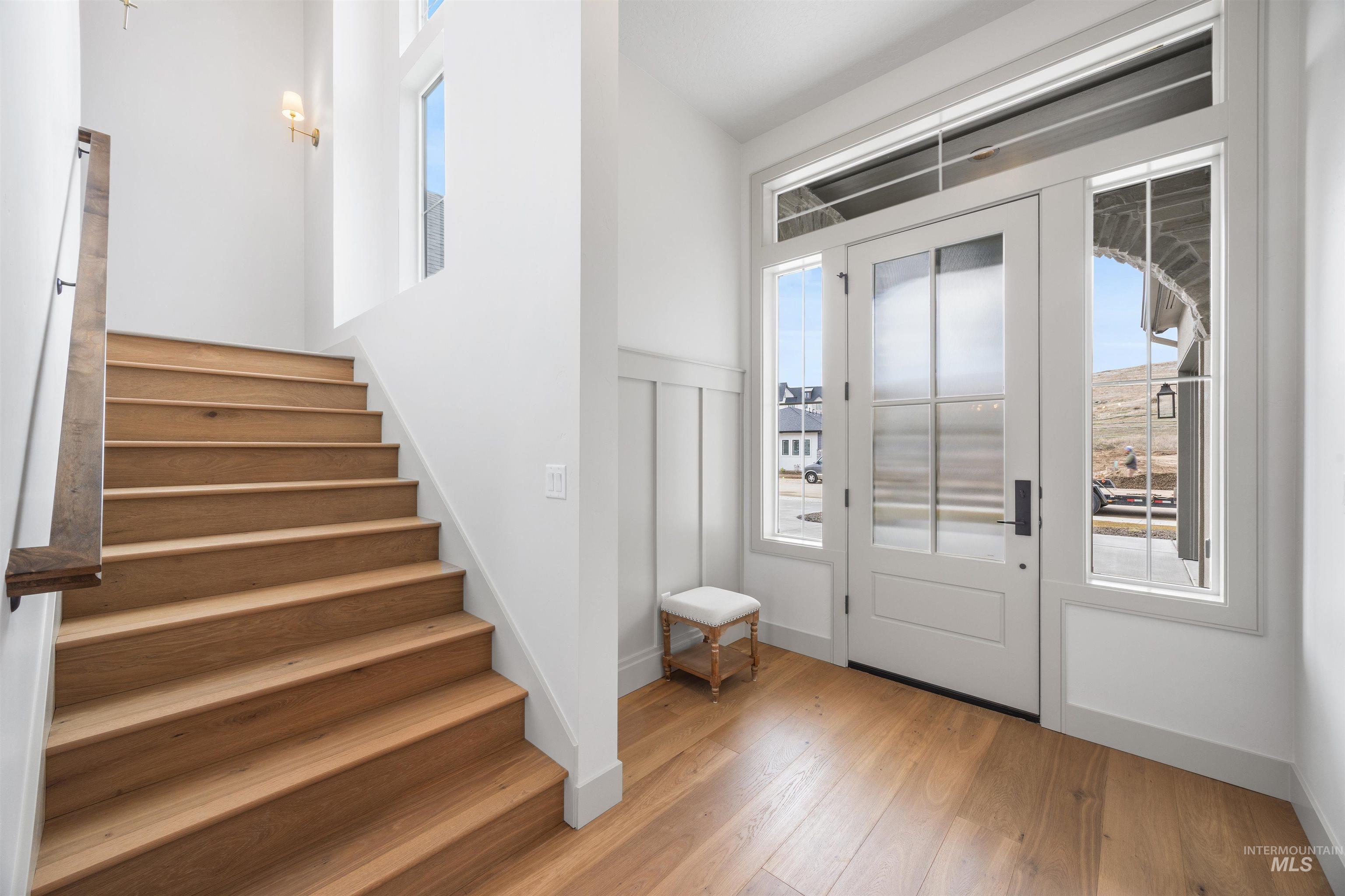 Entryway featuring healthy amount of natural light, light wood finished floors, and a wainscoted wall