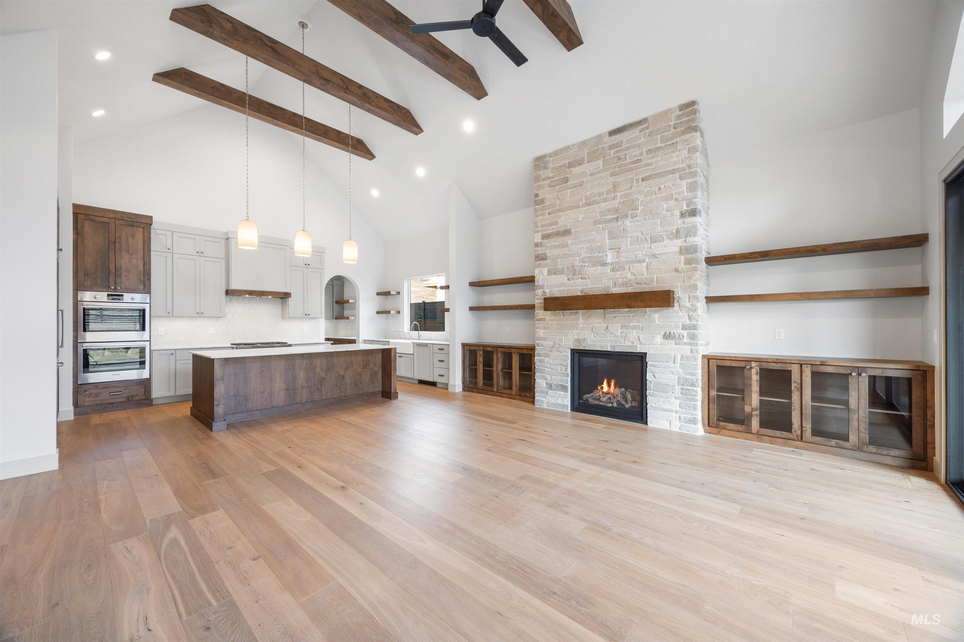 Unfurnished living room with a stone fireplace, light wood finished floors, lofted ceiling, and recessed lighting
